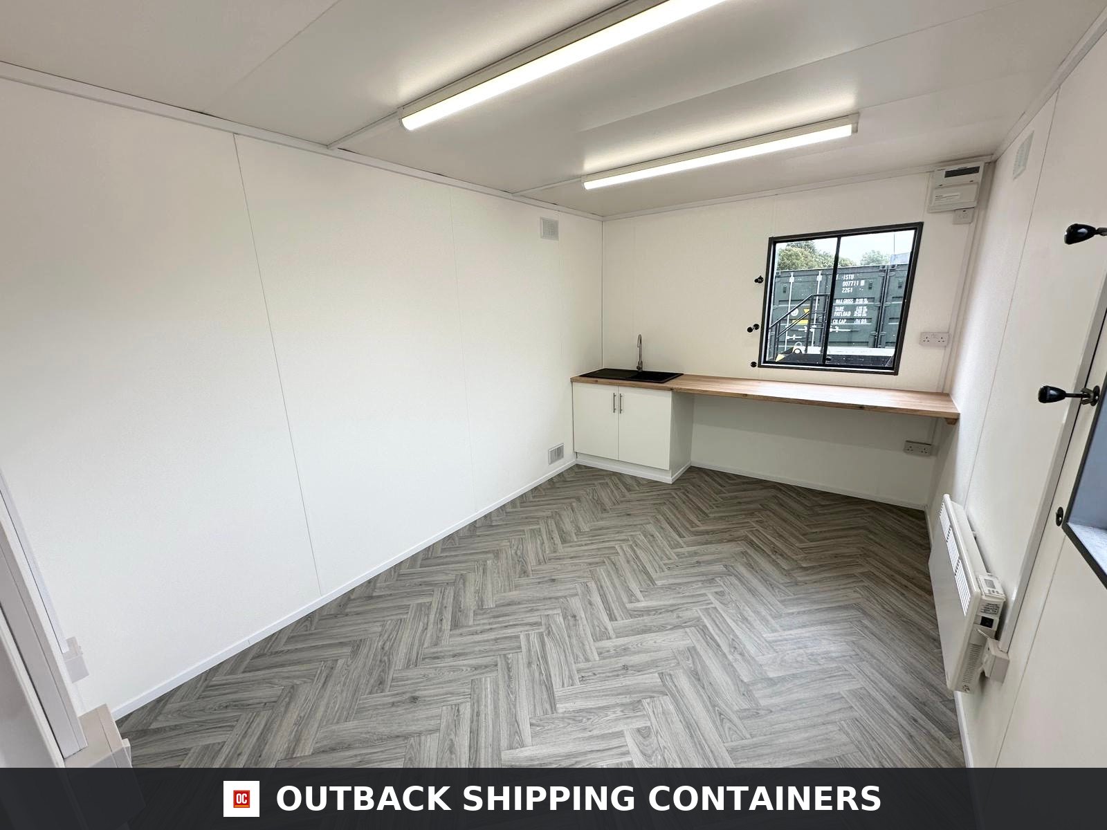 32x10Ft for Sale — Roof and Structural Detail | Outback Shipping Containers Interior view of a portable office cabin with gray herringbone flooring, white walls, and two large windows