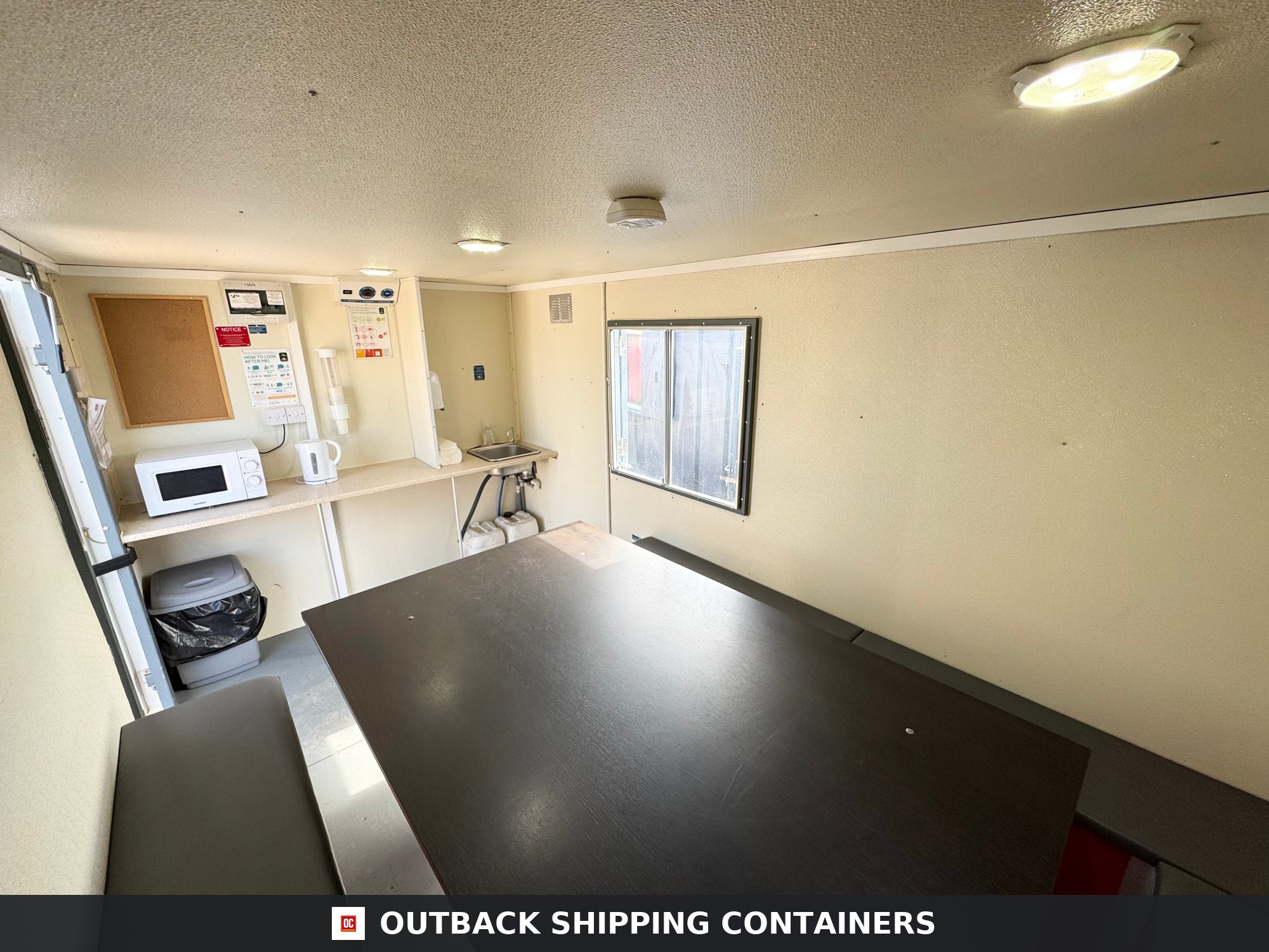 Groundhog Towable Mobile Welfare | 2019 Twin Axle 16ft Welfare — Three-Quarter Angle View Interior of a Groundhog GPO500 mobile welfare unit showing a large dining table, bench seating, and a kitchenette area