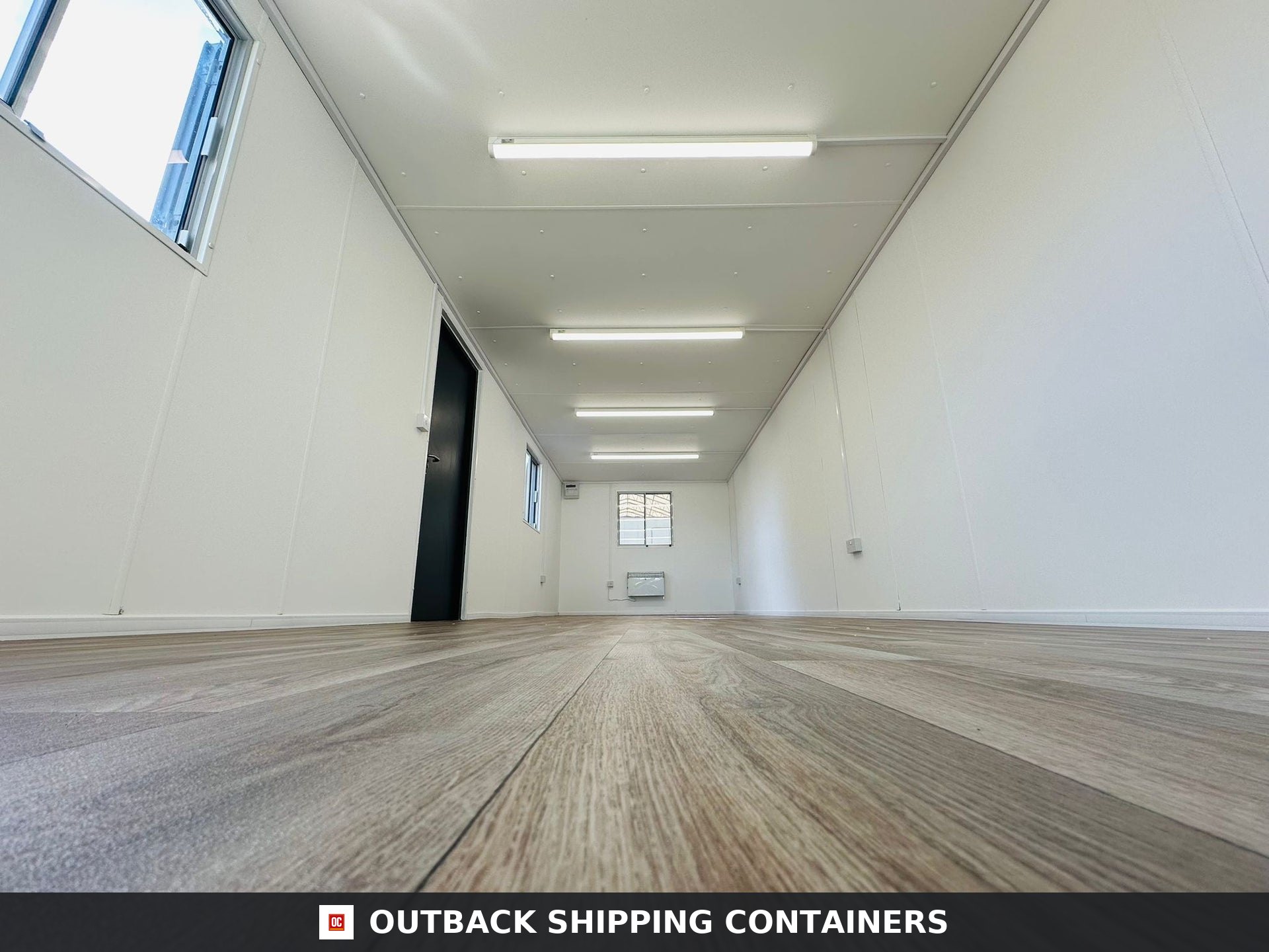 32ft Cabin for Sale — Three-Quarter Angle View | Outback Shipping Containers 2 3 Interior view of a 32ft refurbished portable cabin office with wood flooring, white walls, and overhead lighting