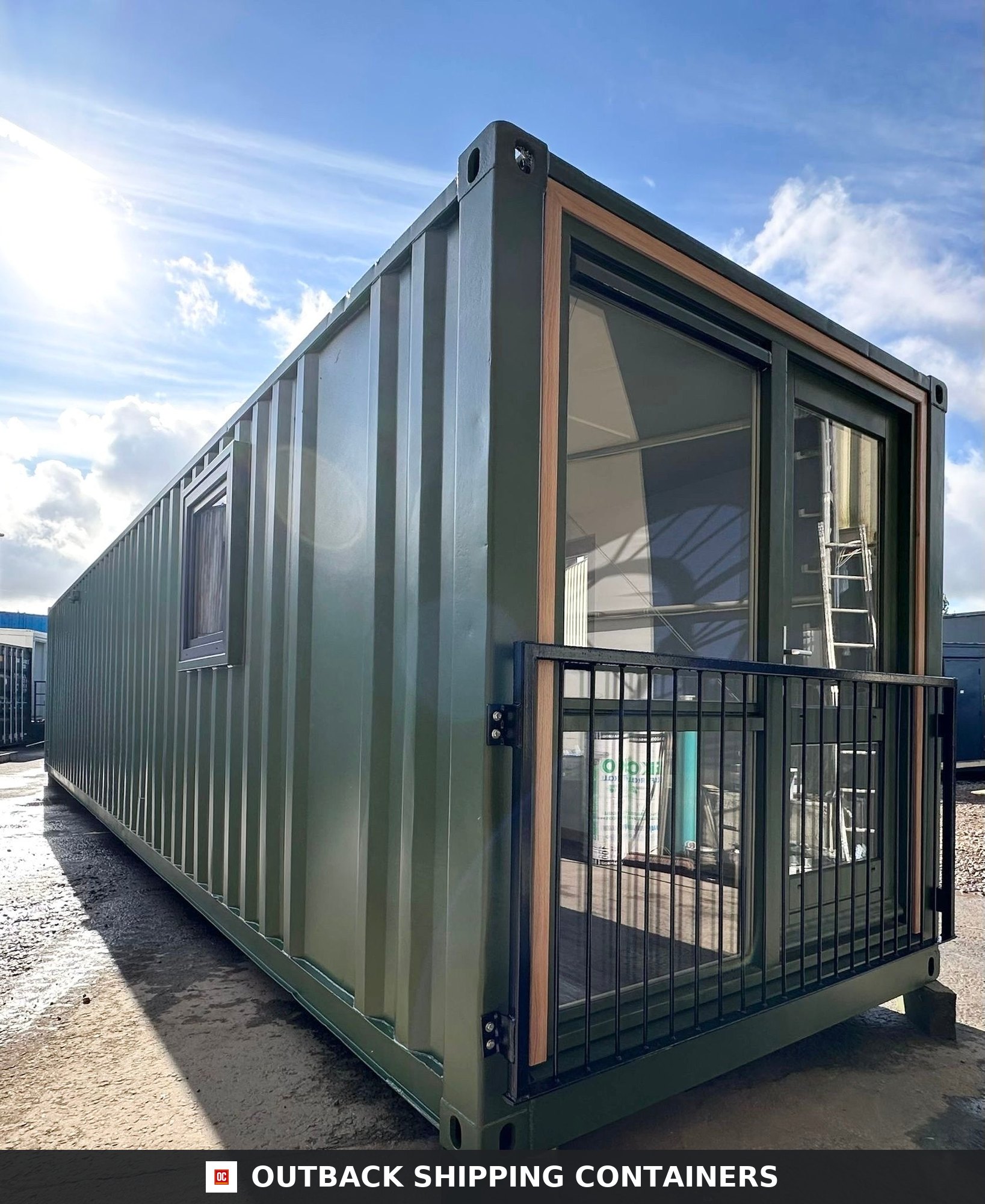 40ft green converted shipping container office with large glass windows and black metal balcony railing