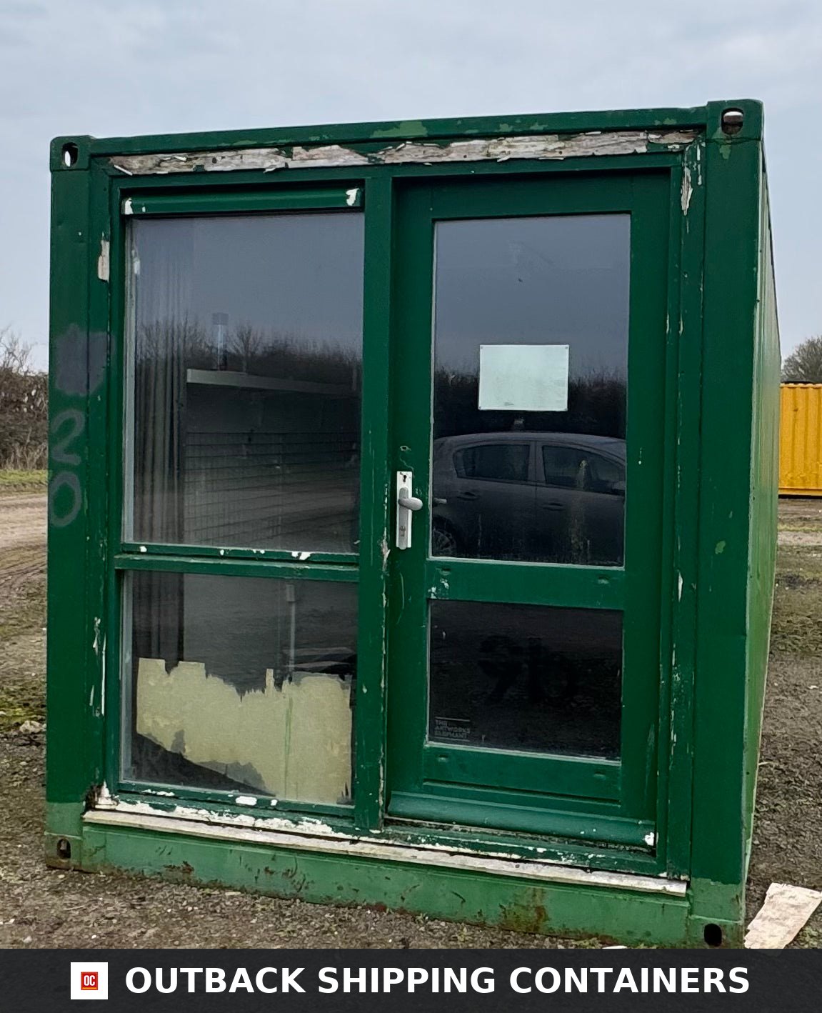 40 Ft Converted Shipping Container 40FT — Door and Entry Detail | Outback Shipping Containers 40ft converted shipping container office entry with green metal frame and large glass windows on gravel