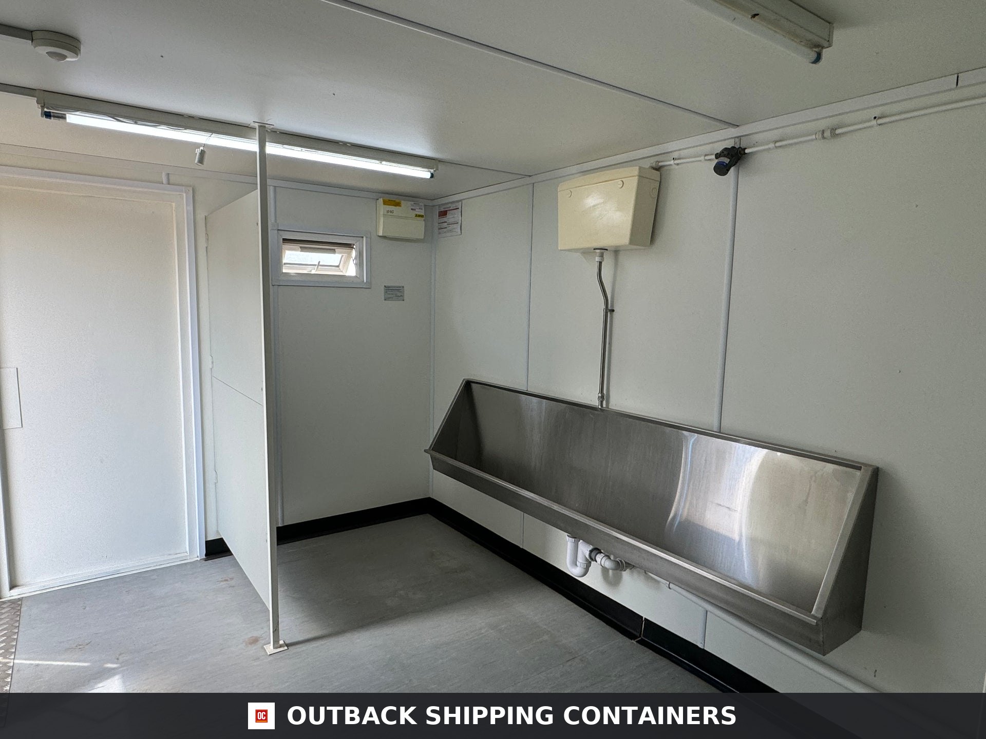 21x8ft for Sale — Rear Exterior View | Outback Shipping Containers Interior view of a portable building restroom featuring a long stainless steel trough urinal and vinyl flooring
