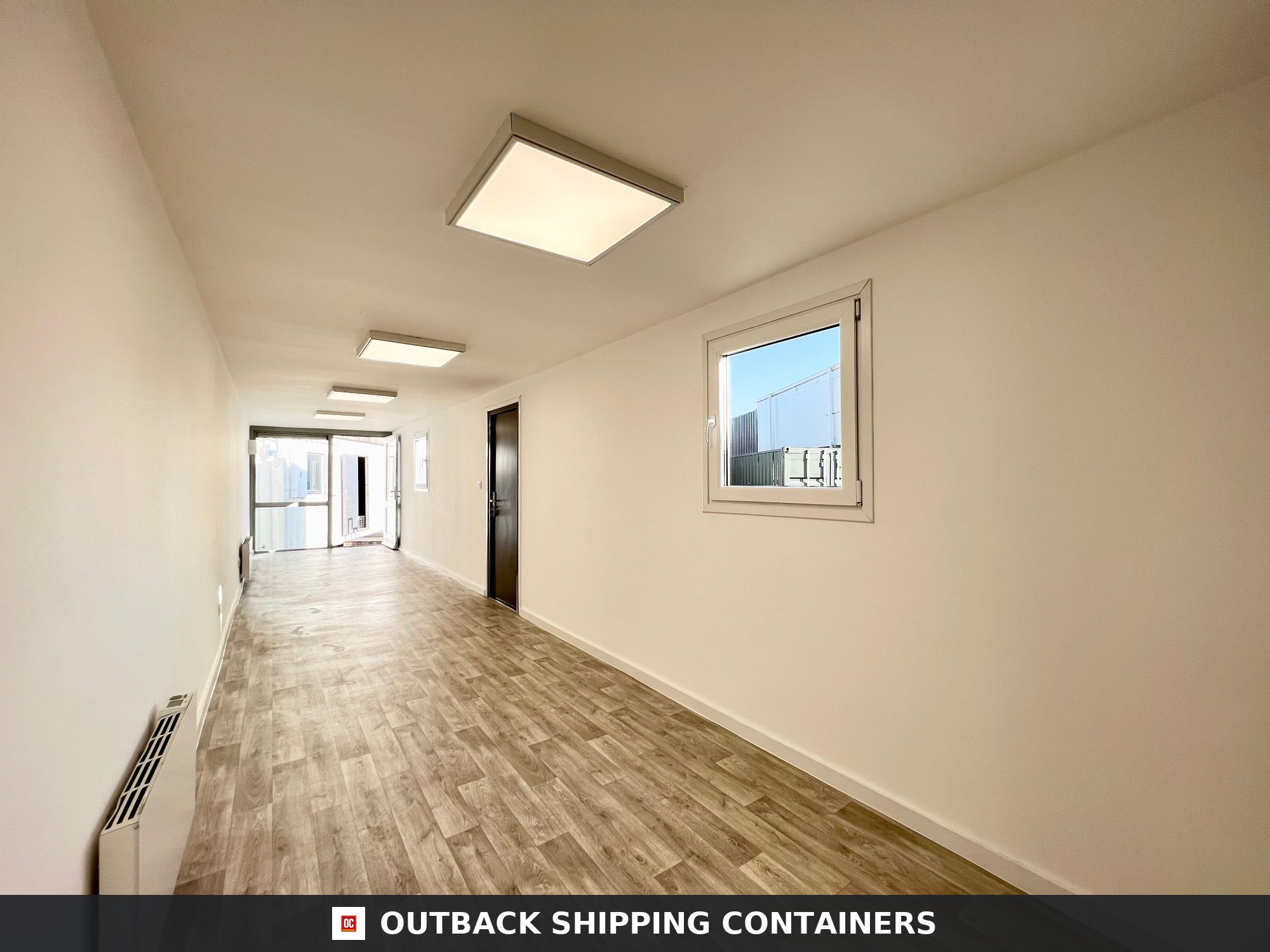 40ft shipping container office interior with wood-style flooring, white walls, square LED lights, and a window