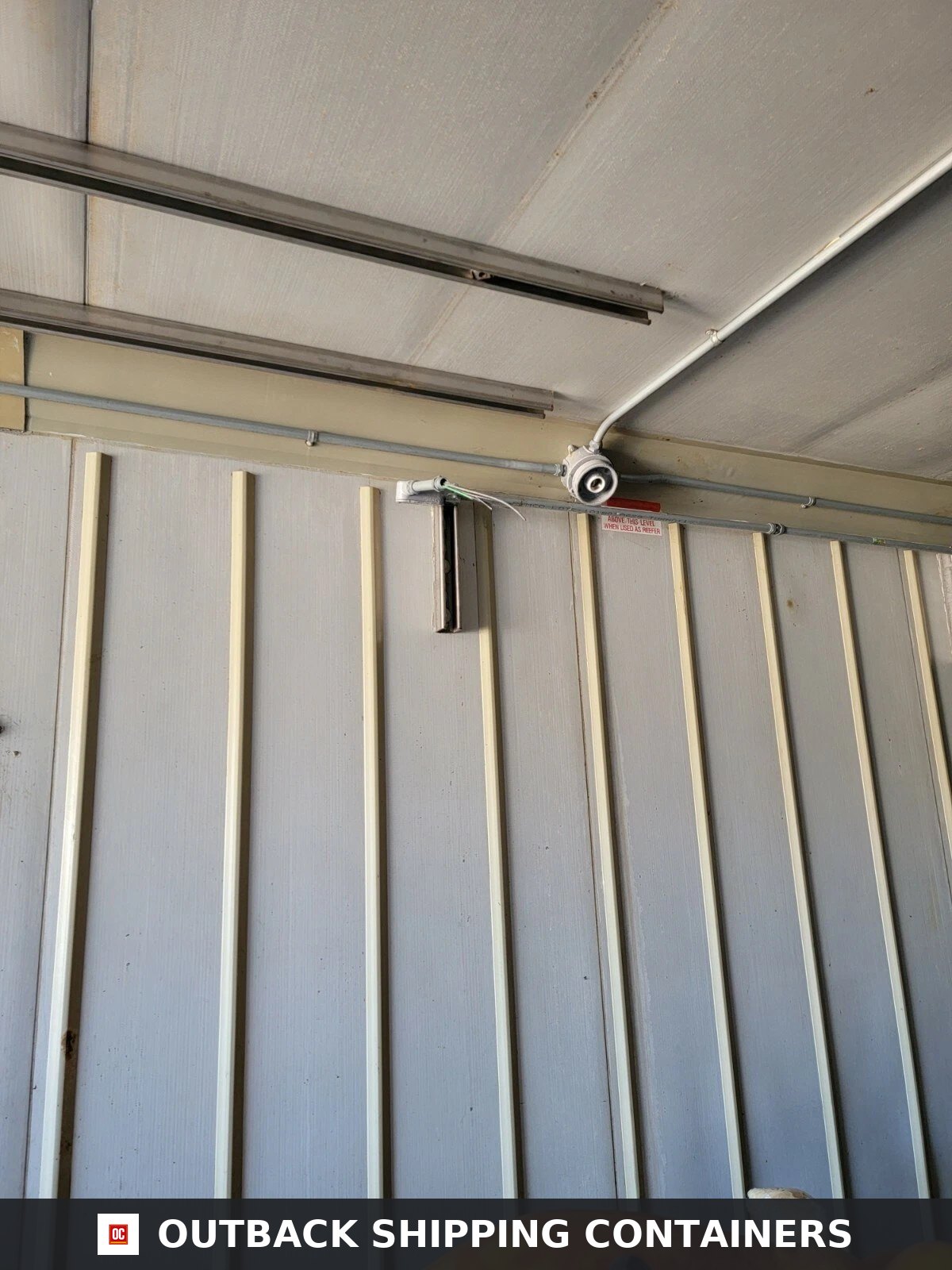 Interior corner of a Stoughton 40ft storage container showing white conduit, electrical wiring, and vertical ribbing