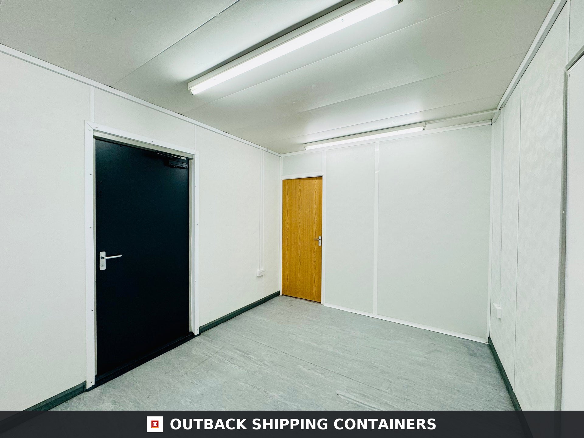 32x10ft for Sale — Three-Quarter Angle View | Outback Shipping Containers Interior view of a 32x10ft refurbished container featuring white paneled walls, a black metal door, and one wood door