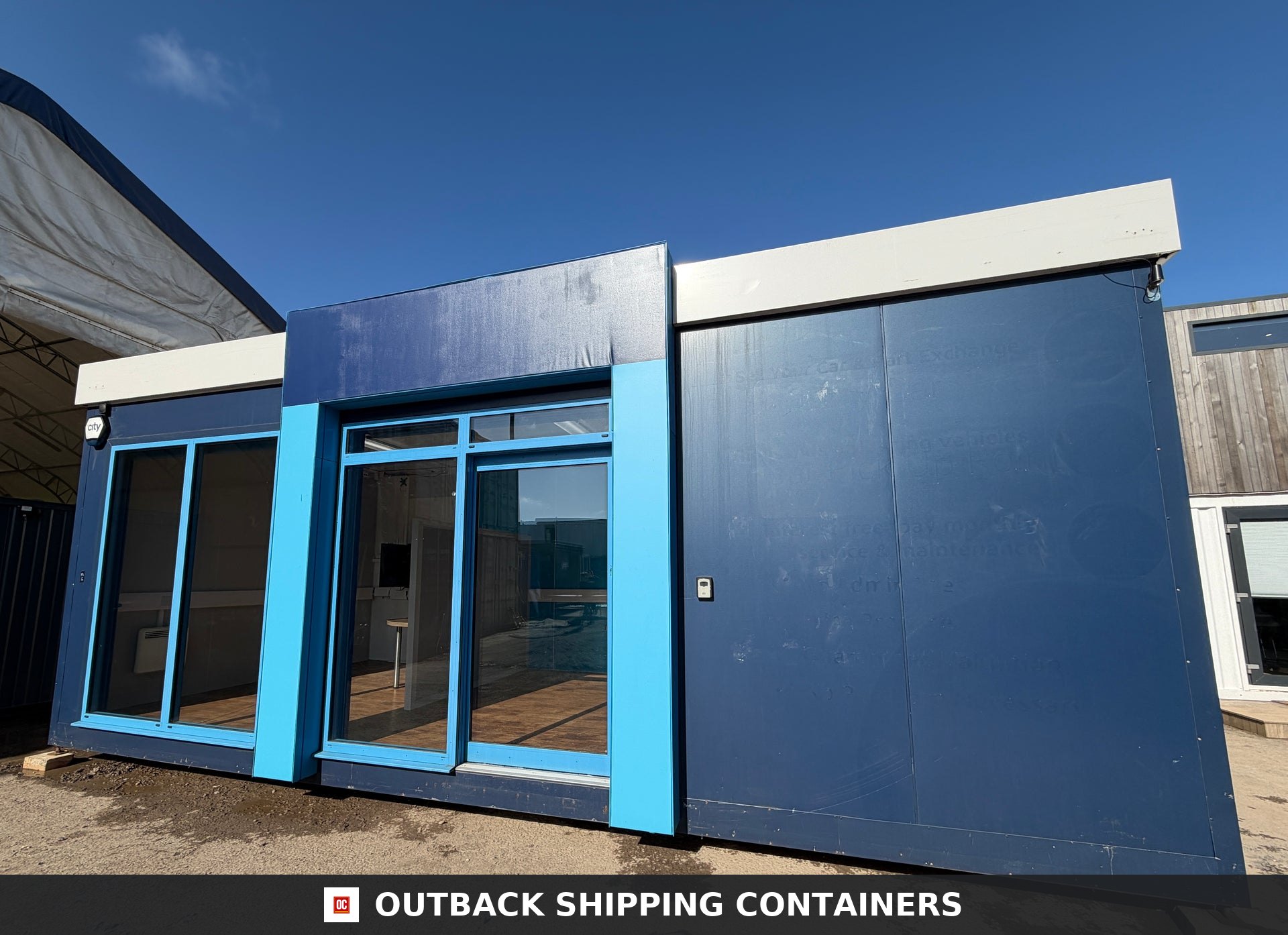 26x12ft for Sale — Rear Exterior View | Outback Shipping Containers Refurbished 26x12ft portable marketing suite featuring blue multi-tone exterior siding and large glass entrance doors