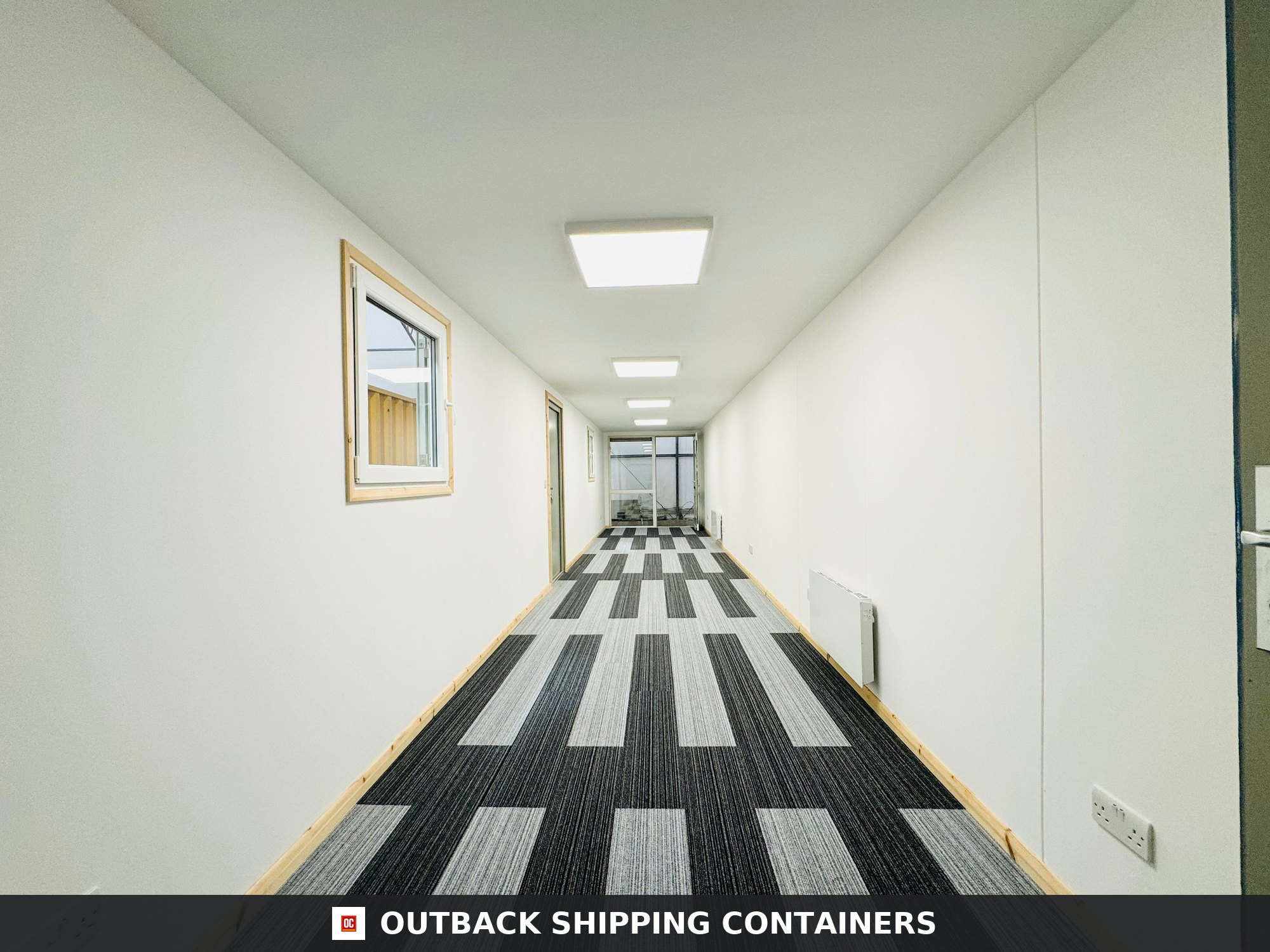 Interior view of a 40ft shipping container office with white walls, carpet tiles, and square ceiling lights