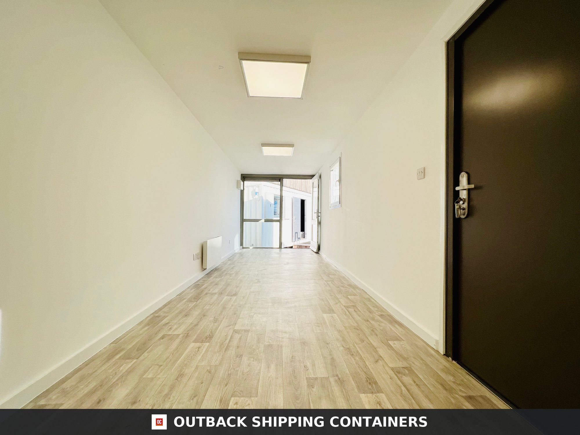 40ft shipping container office interior with wood-style flooring, white walls, and bright overhead square LED lighting