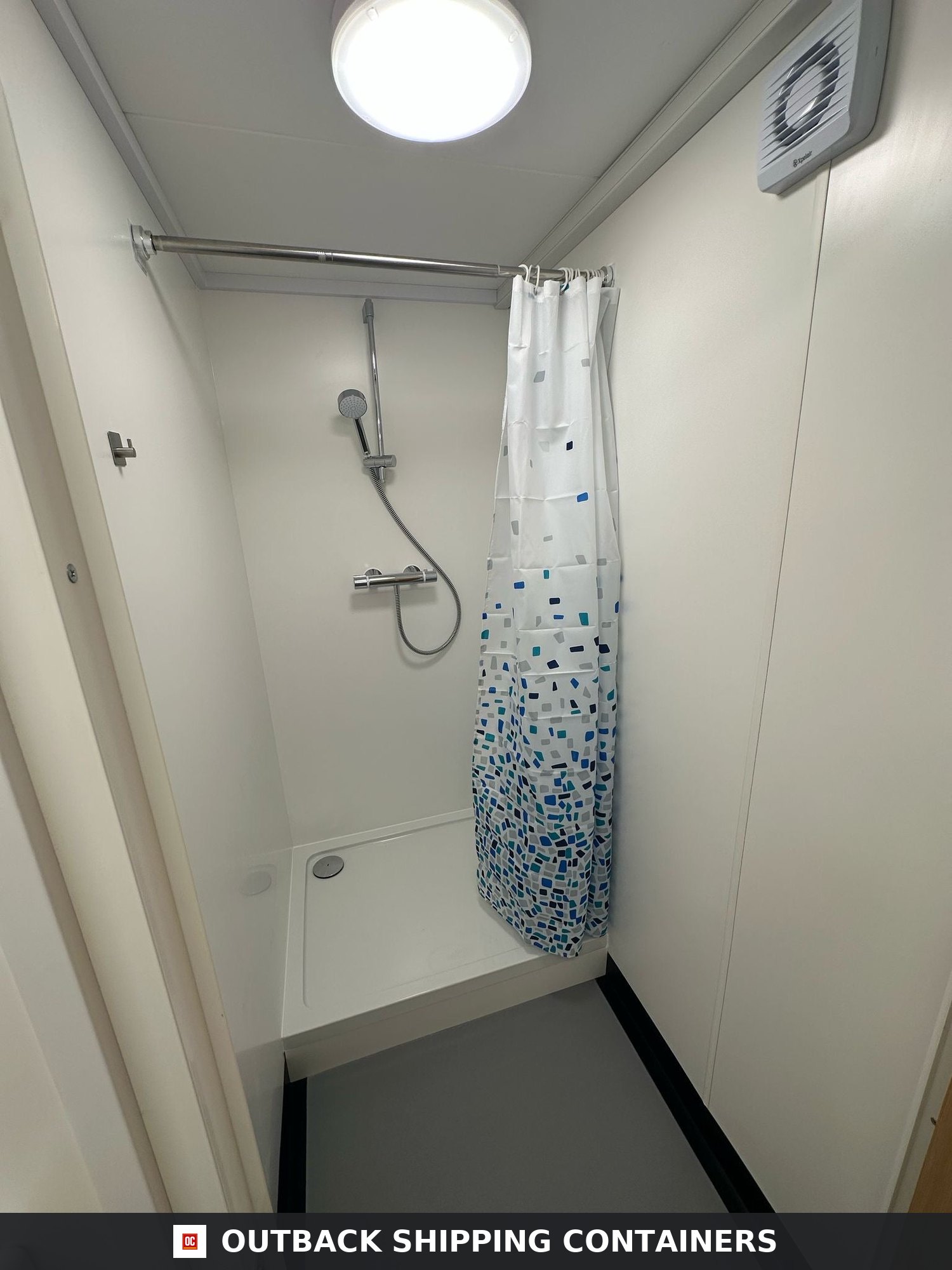 40x8ft for Sale — Interior View | Outback Shipping Containers 2 Interior shower cubicle in a 40ft custom shipping container welfare unit with white walls and a blue pattern curtain