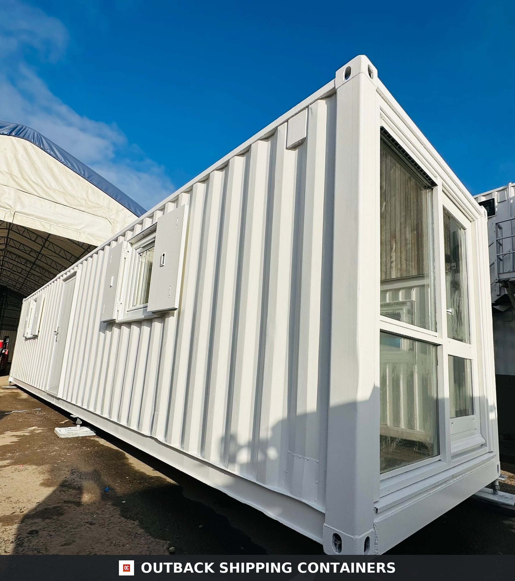 40ft white converted shipping container office with side windows and a large glass end panel outdoors