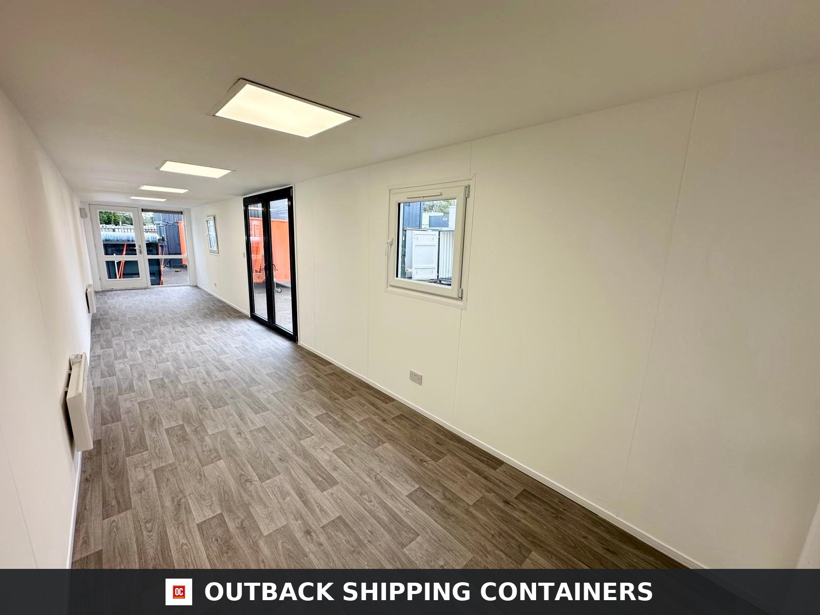40ft shipping container office interior with wood plank flooring, white walls, LED lighting, and glass doors