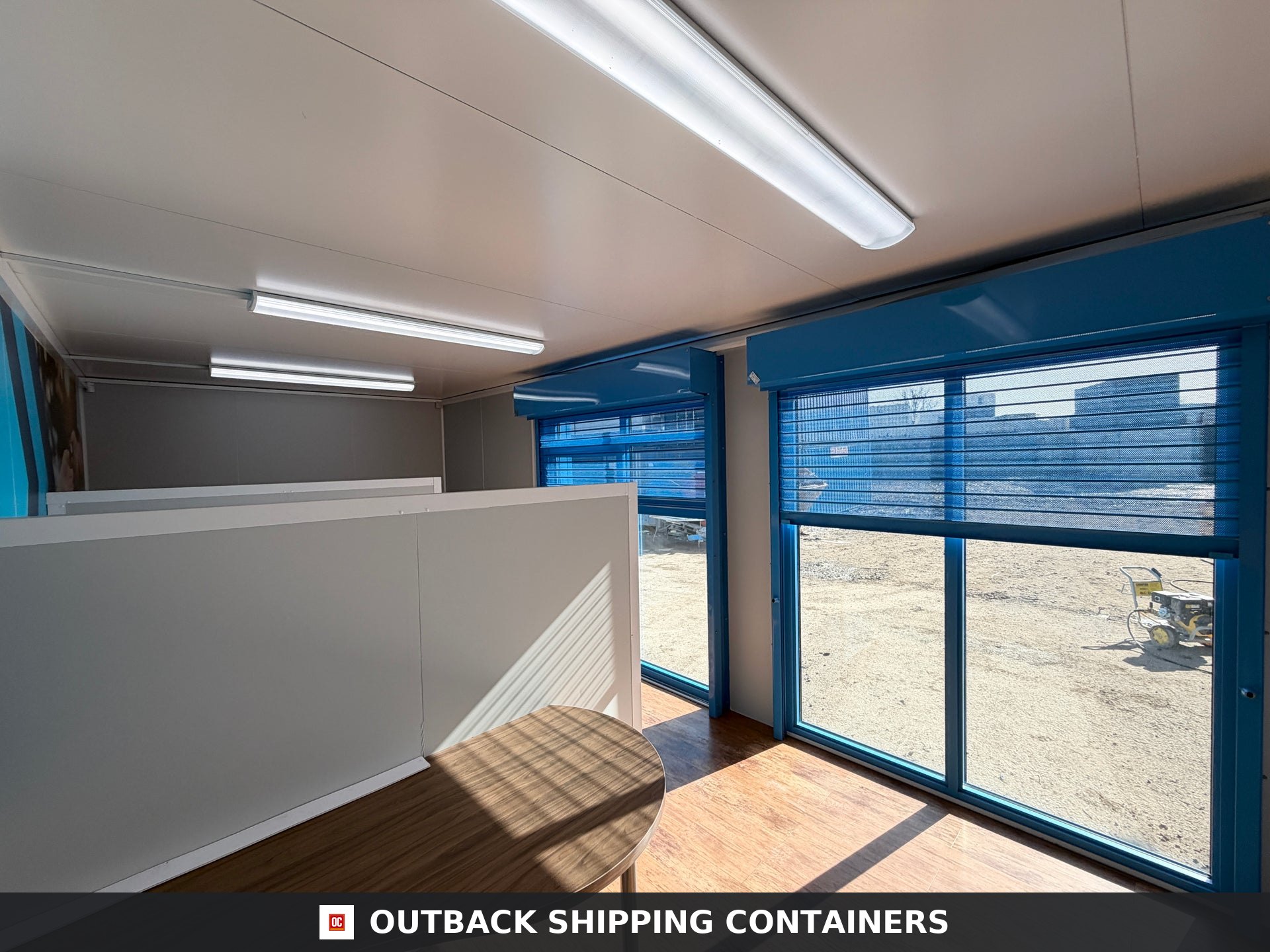 26x12ft for Sale — Window and Shutter Detail | Outback Shipping Containers Exterior view of a navy blue 26x12 marketing suite with large light blue glass windows on a sunny day