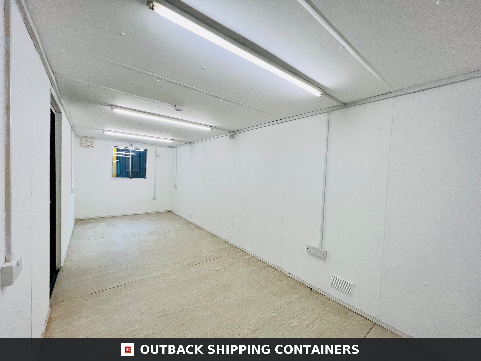 Interior view of a 24x9 ft shipping container office with white walls, linoleum flooring, and overhead lighting