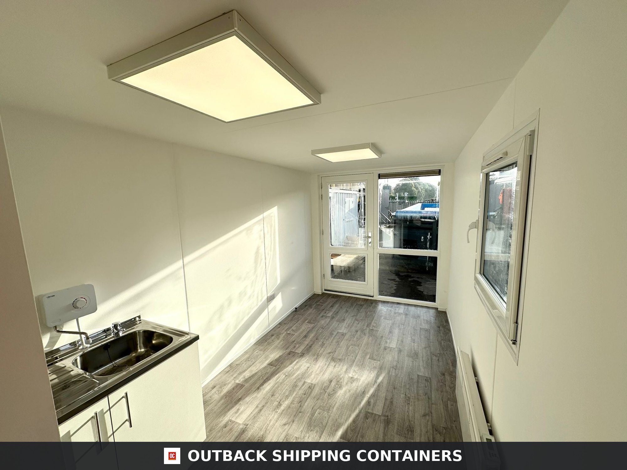 Interior of 40ft container office conversion with kitchenette and gray wood flooring