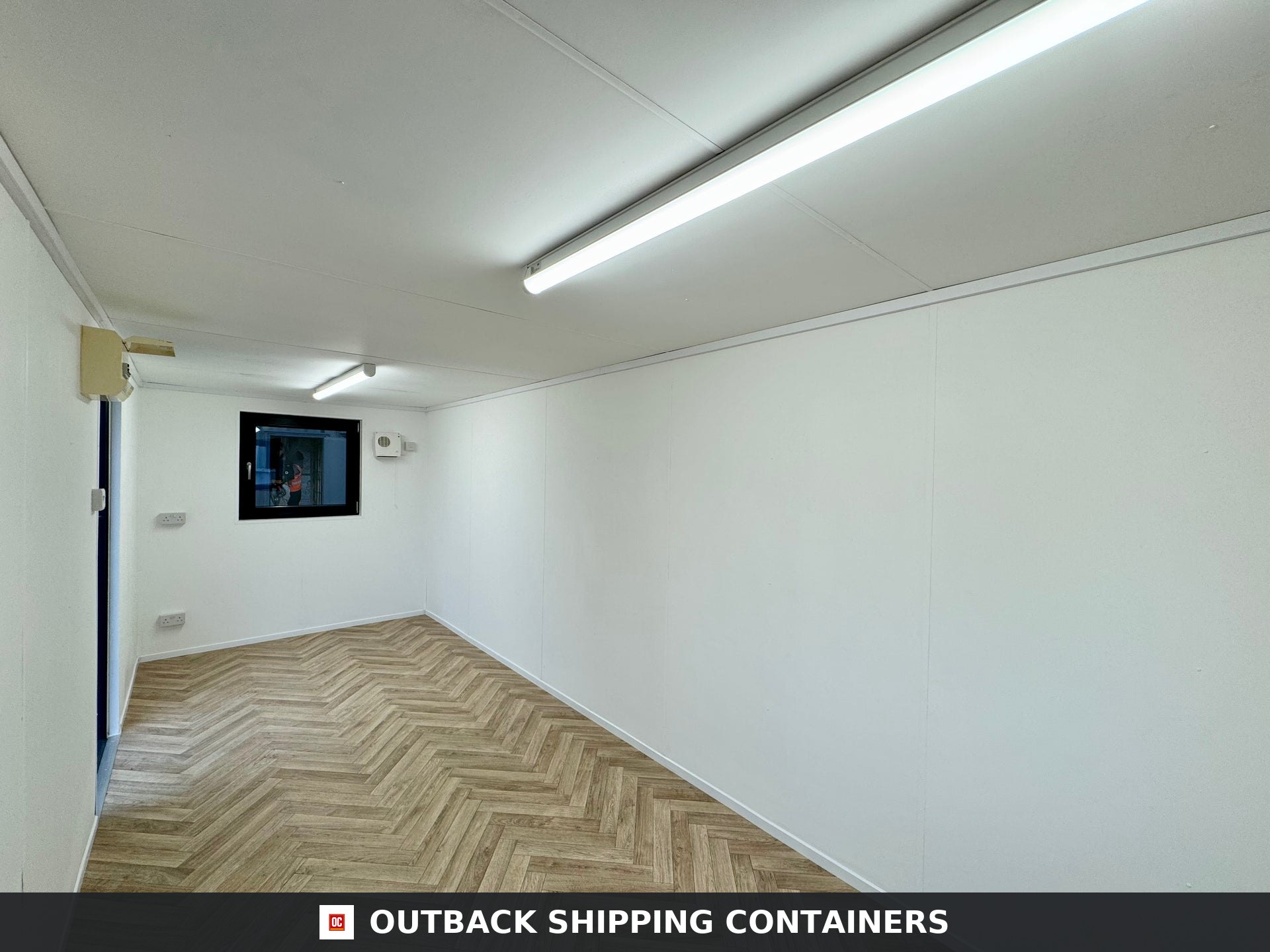 21x8ft Office Container for Sale — Window and Shutter Detail | Outback Shipping Containers 21x8ft gray mobile office shipping container with windows and security shutters on a paved lot