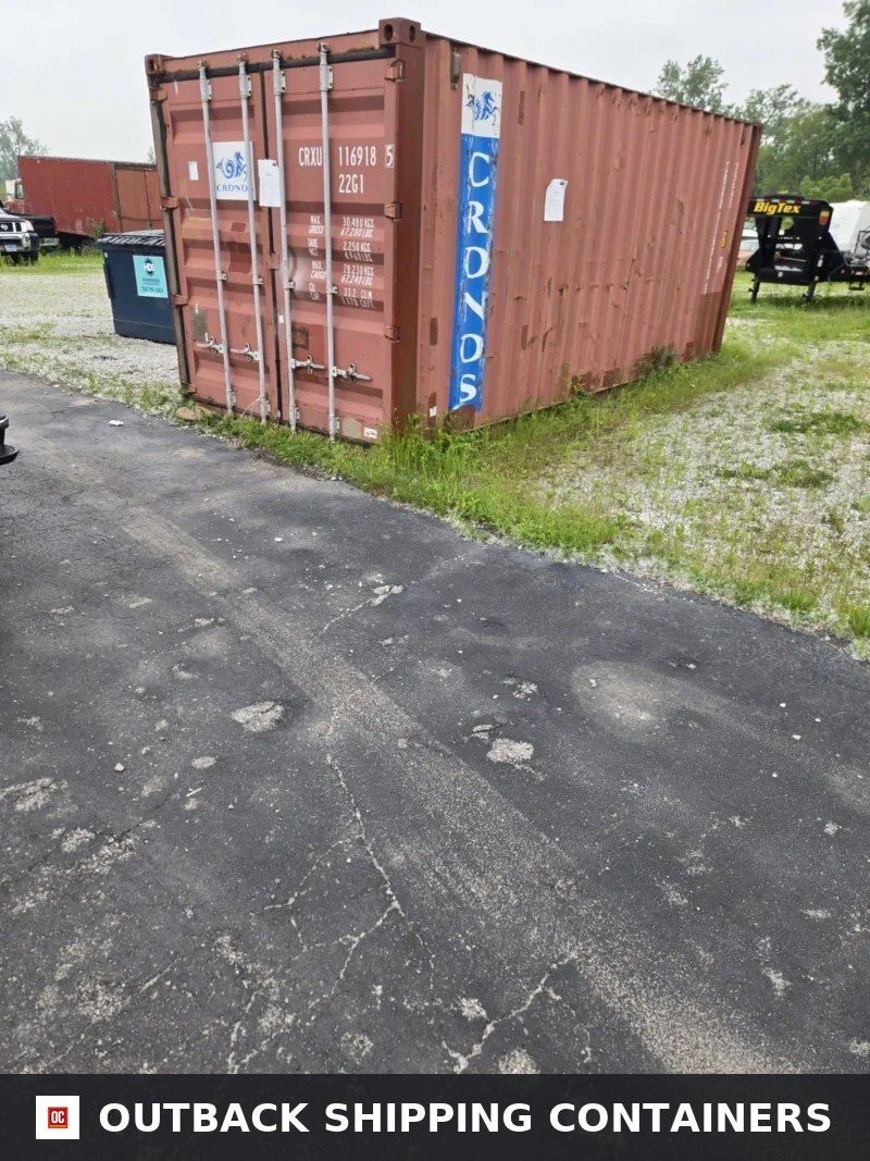 Durable & Affordable Used 20′ Storage Containers / Storage Pods for Sale — Rear Exterior View Used 20ft storage container in rust red color on a gravel and grass lot showing closed cargo doors and side logo