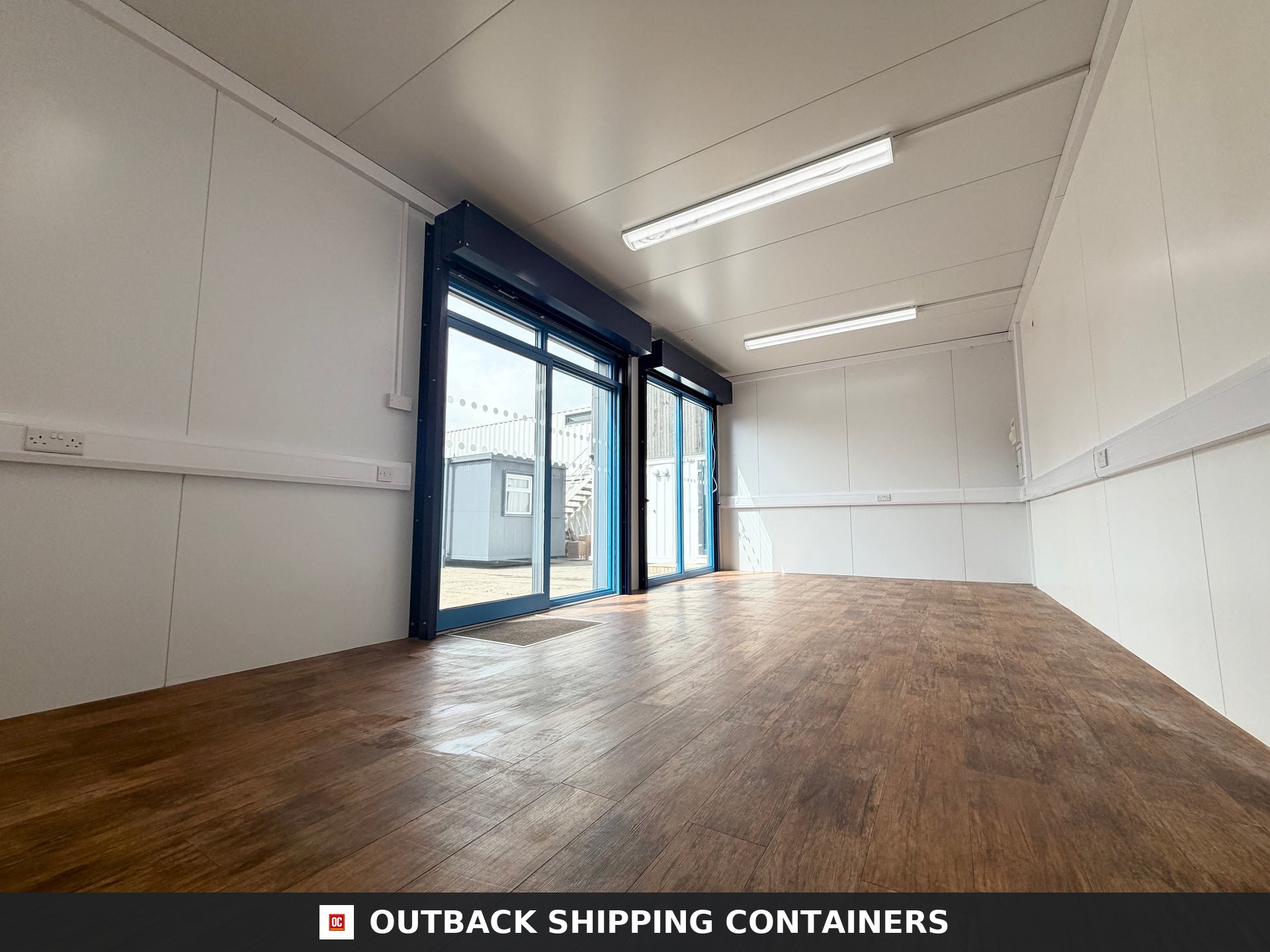 26x12ft for Sale — Window and Shutter Detail | Outback Shipping Containers Interior of a refurbished 26x12ft portable sales pod featuring wood flooring, white walls, and large glass sliding doors