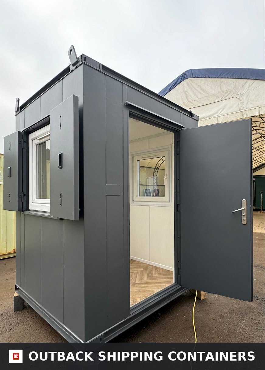 6x6 ft 6x6FT for Sale — Side Profile View | Outback Shipping Containers Dark grey 6x6 ft anti-vandal gate house office with open steel door and window shutters revealing wood-style flooring