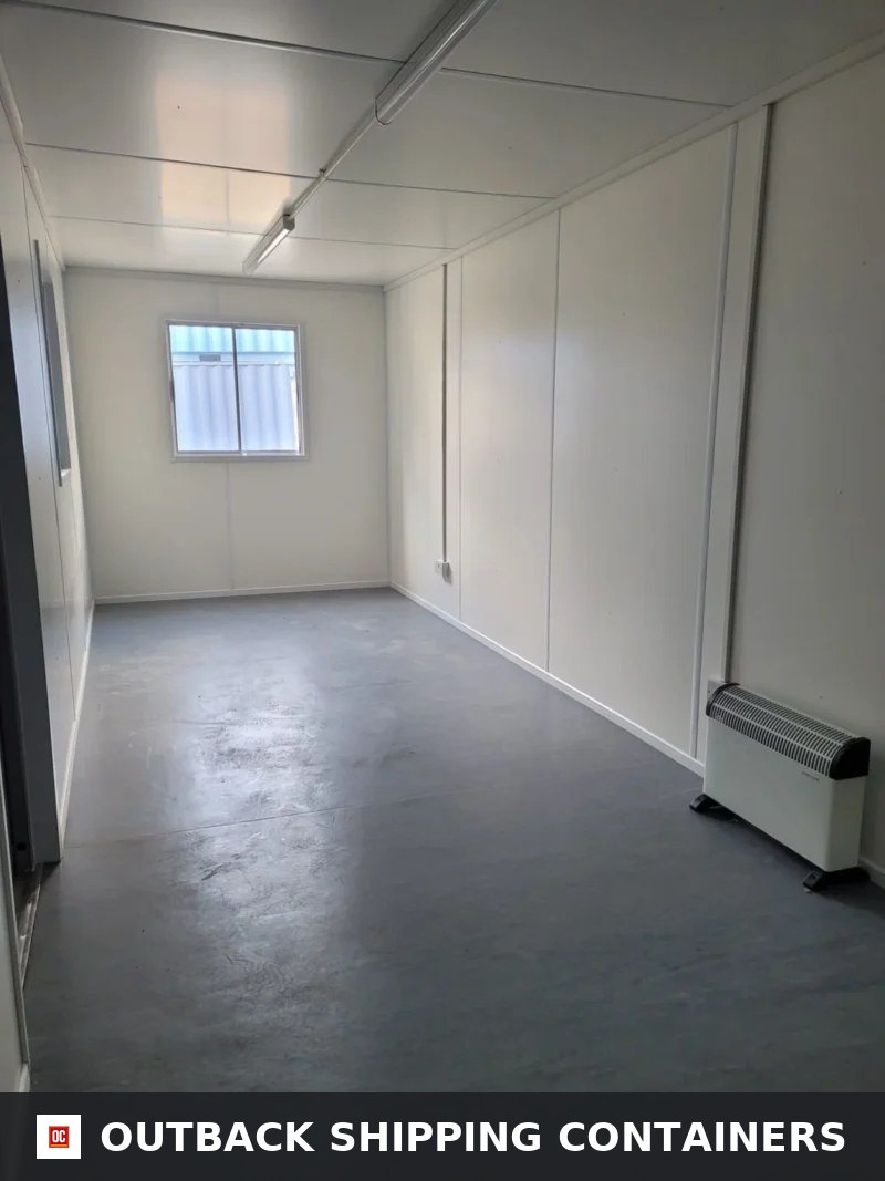 Interior view of a 30ft ModiBox container office with white paneled walls, gray flooring, window, and electric heater