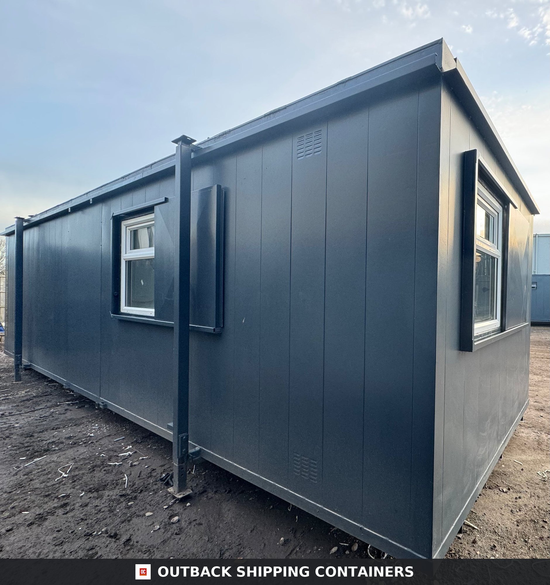 32ft Cabin for Sale — Rear Exterior View | Outback Shipping Containers 2 Interior of a refurbished 32ft container office with herringbone wood flooring, white walls, and a black steel entry door