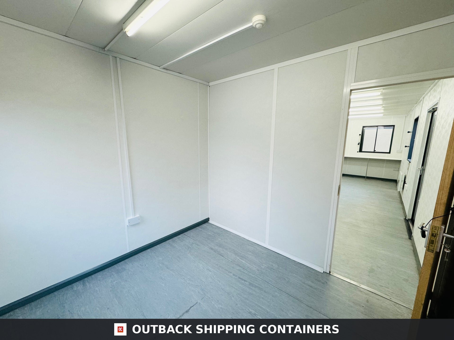 32x10ft for Sale — Interior View | Outback Shipping Containers Refurbished 32ft shipping container office interior with white paneled walls and gray vinyl flooring
