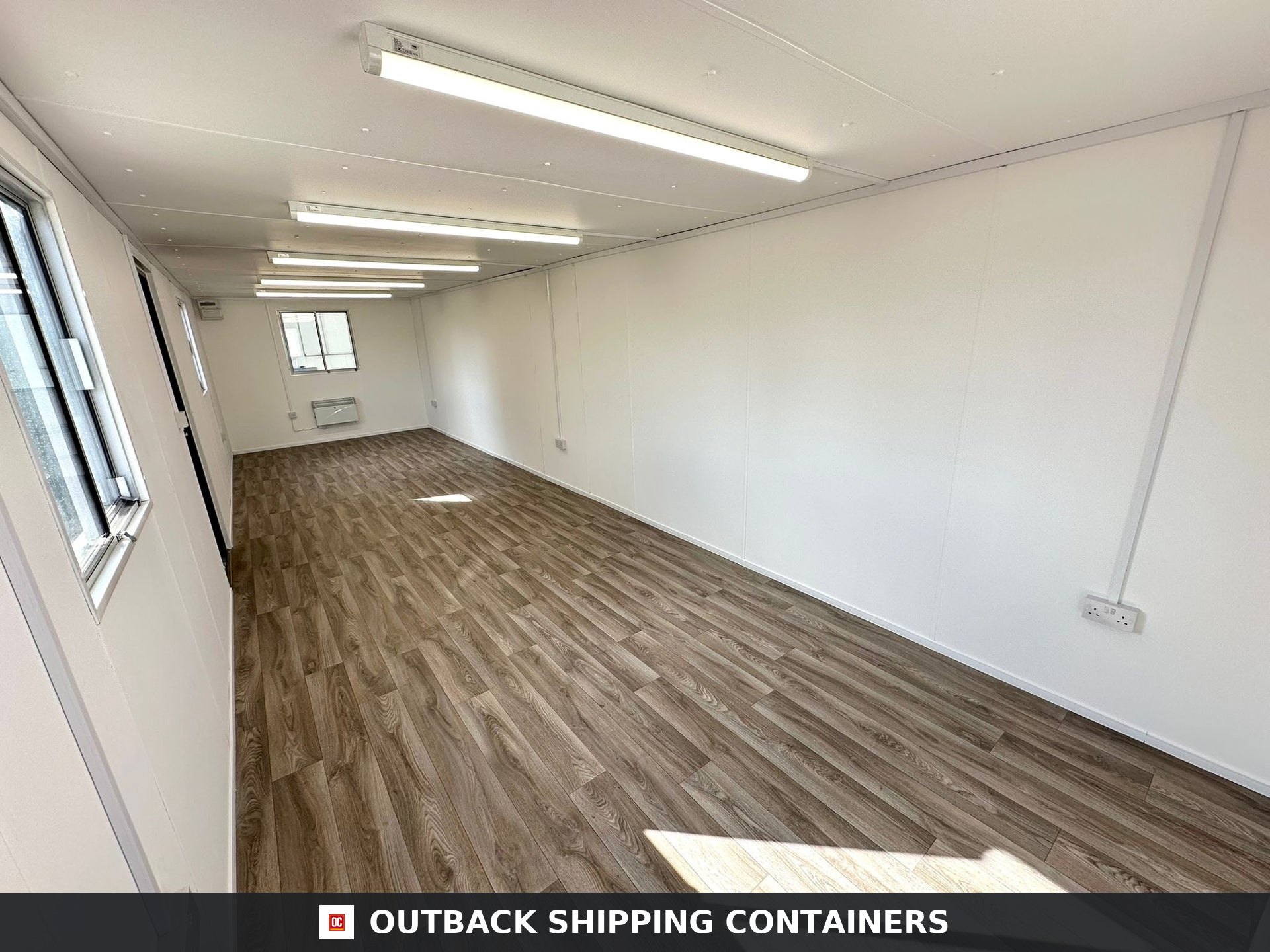 32ft Cabin for Sale — Door and Entry Detail | Outback Shipping Containers 2 3 Interior view of a 32ft container office with wood-style flooring, white walls, and overhead LED lighting