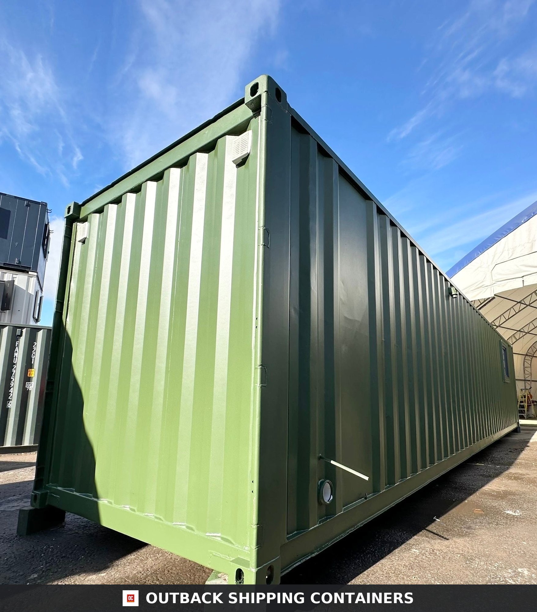 40ft green shipping container office with corrugated steel walls and small window under a blue sky