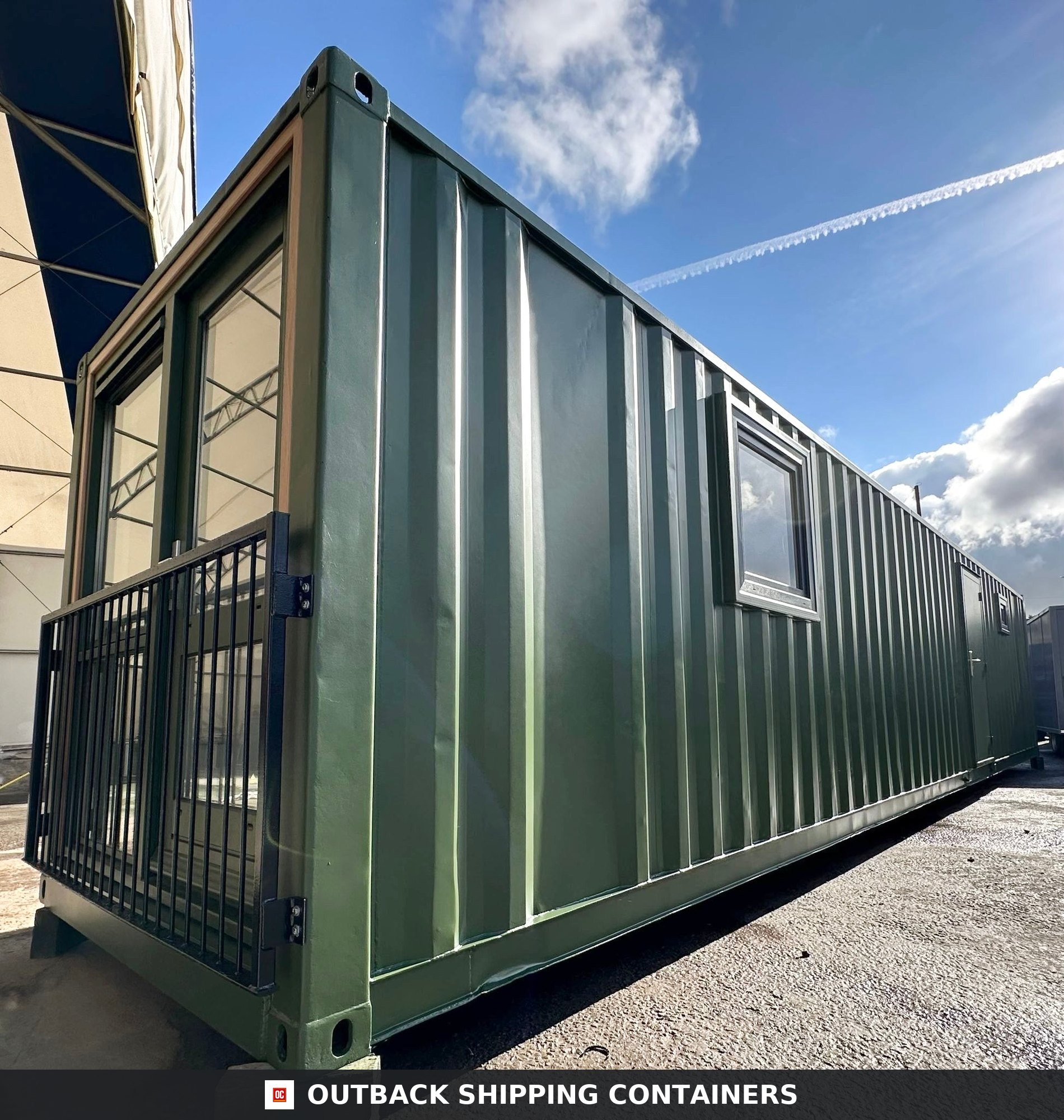 40ft green shipping container office with a full-height glass door, black metal railing, and side windows
