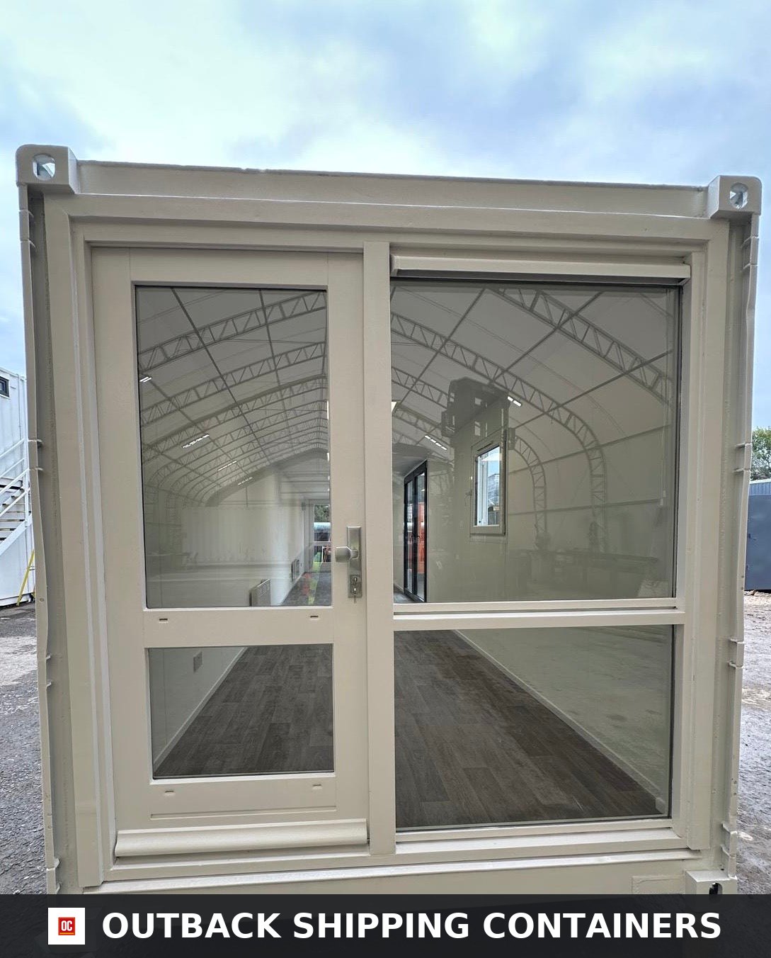 40ft office container with glass door and large picture window revealing wood flooring and an open plan interior layout