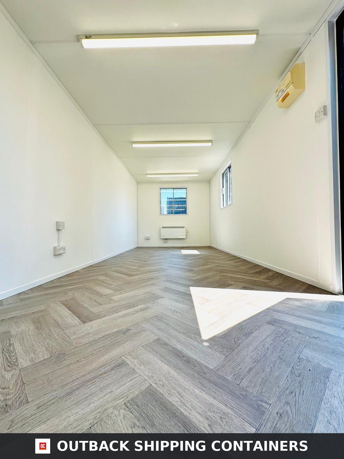 24x9 ft 24x9FT for Sale — Rear Exterior View | Outback Shipping Containers 24x9 ft open plan portable office interior with white walls, herringbone flooring, overhead lights, and a heater