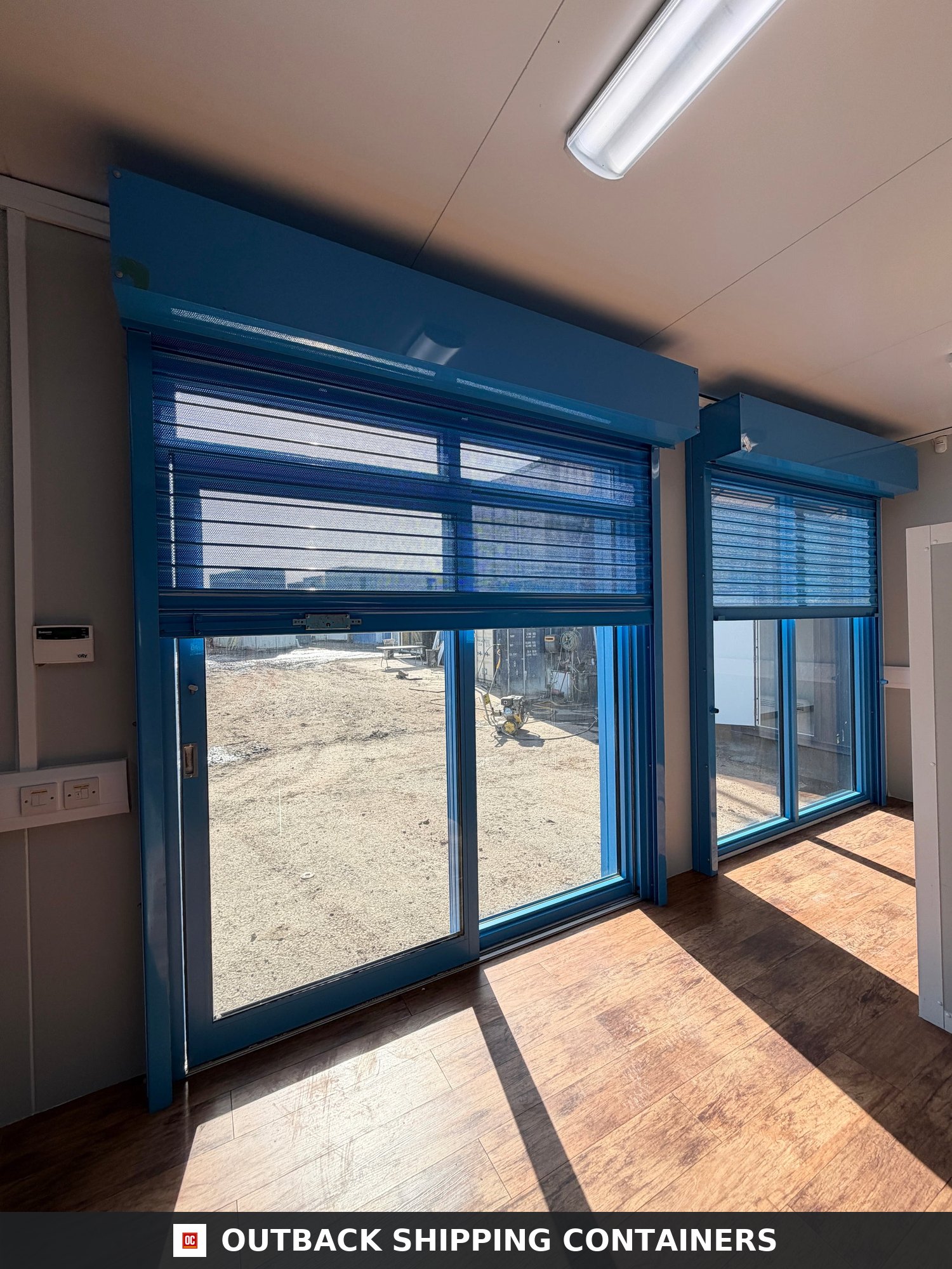 26x12ft for Sale — Corner Casting and Frame Detail | Outback Shipping Containers Blue 26ft marketing suite portable building with glass sliding doors and light blue accents under a bright sky
