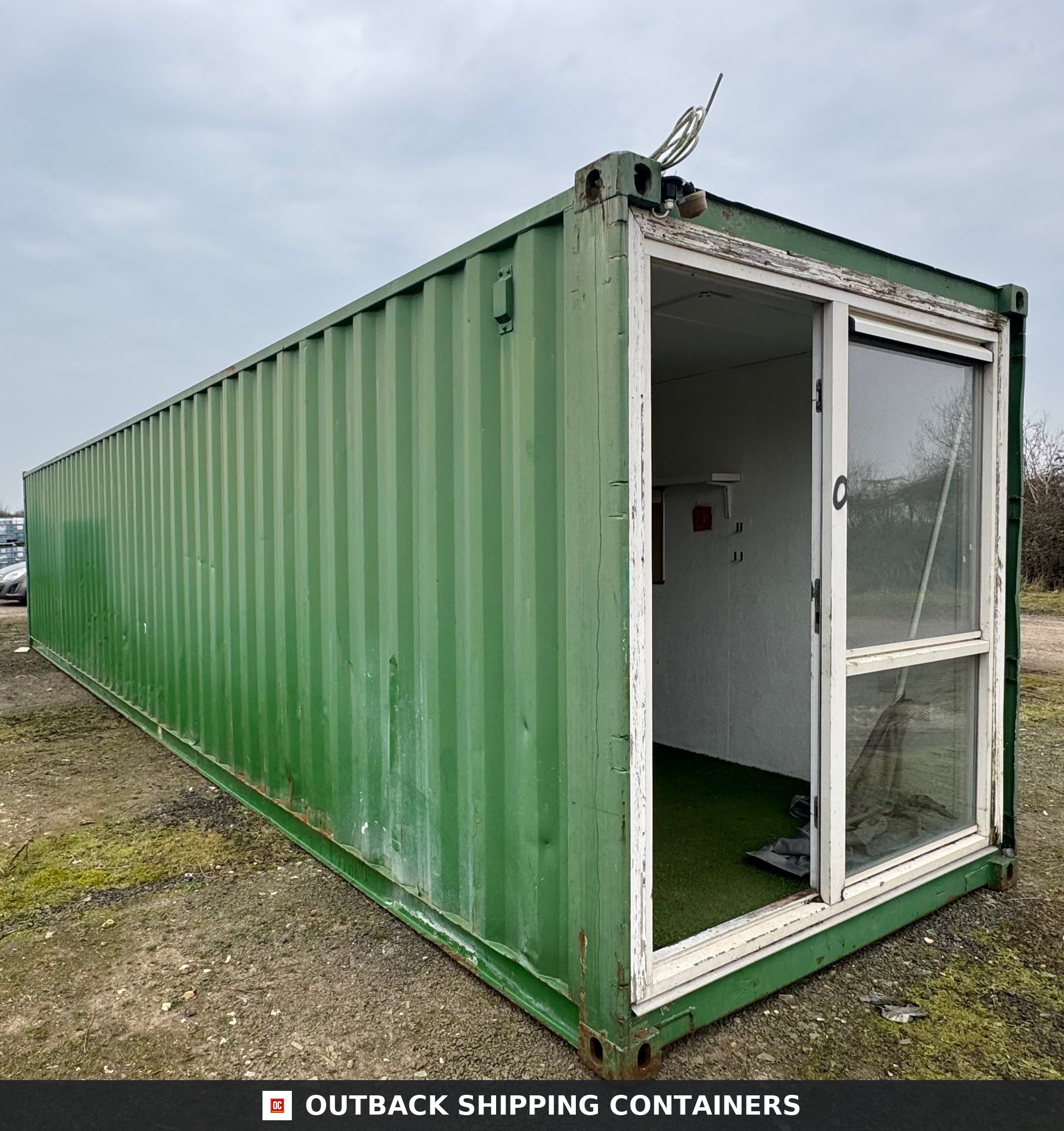 40 Ft Converted Shipping Container 40FT for Sale — Interior View | Outback Shipping Containers Green 40ft shipping container office exterior showing glass sliding door entry on the end panel under a cloudy sky