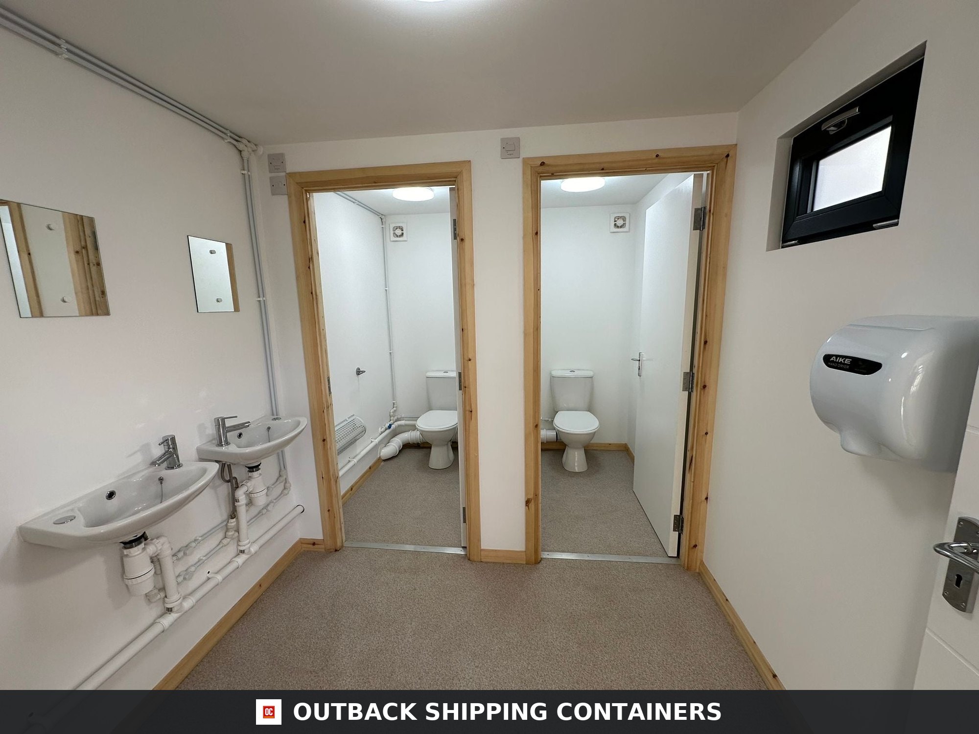 Interior of a refurbished 40ft container office bathroom featuring two sinks and two toilet stalls