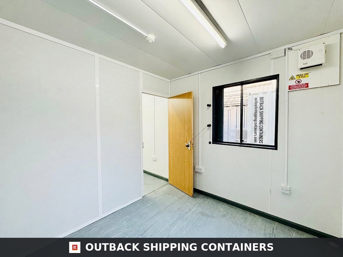 32x10ft for Sale — Interior Detail | Outback Shipping Containers Refurbished 32x10 portable changing room interior with white walls, wood door, black window frame, and overhead lighting