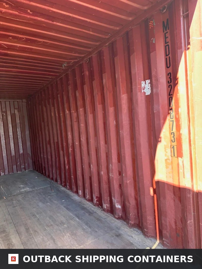 Used 20ft Conex Shipping / Storage Container – Yellow/Gold for Sale — Three-Quarter Angle View Interior view of a used 20ft conex container with red corrugated steel walls and plywood flooring