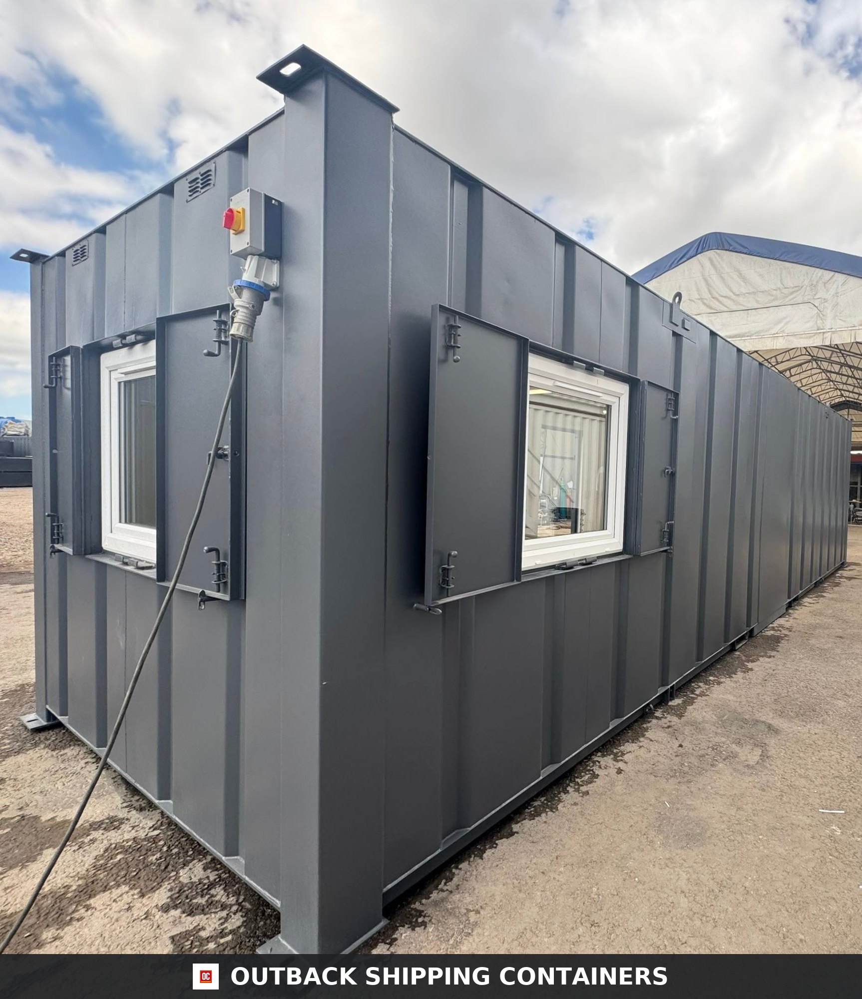 32ft Cabin for Sale — Roof and Structural Detail | Outback Shipping Containers Refurbished 32ft anti-vandal portable cabin with gray steel siding and secure window shutters on a gravel lot