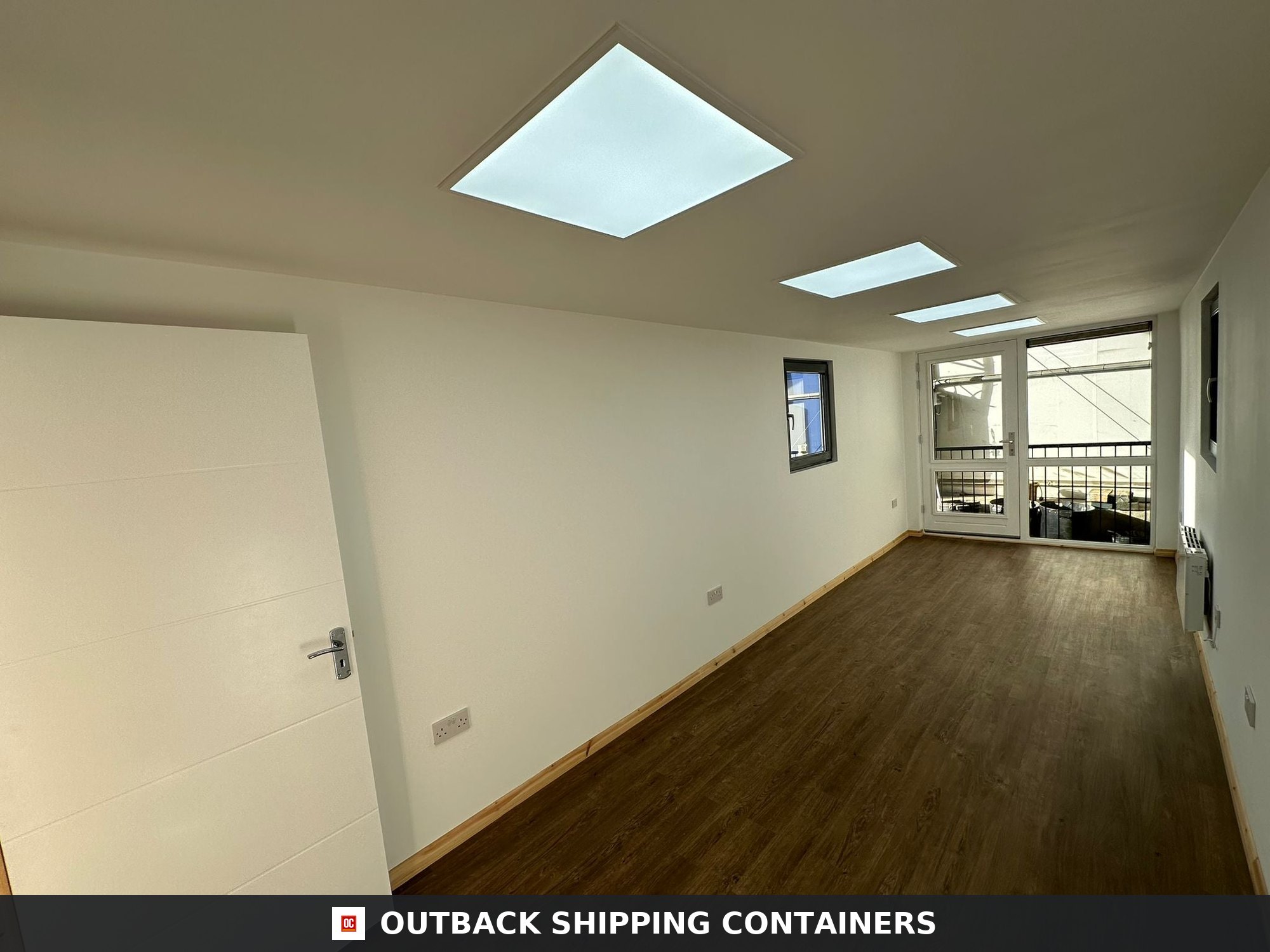 40ft shipping container office interior with wood floors, white walls, and LED ceiling light panels