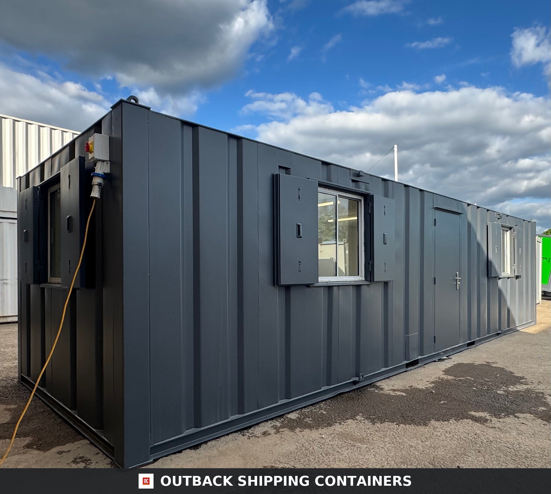 32ft Cabin for Sale — Rear Exterior View | Outback Shipping Containers 2 3 Refurbished 32ft anti-vandal portable cabin with dark gray exterior, security shutters over windows, and electrical input