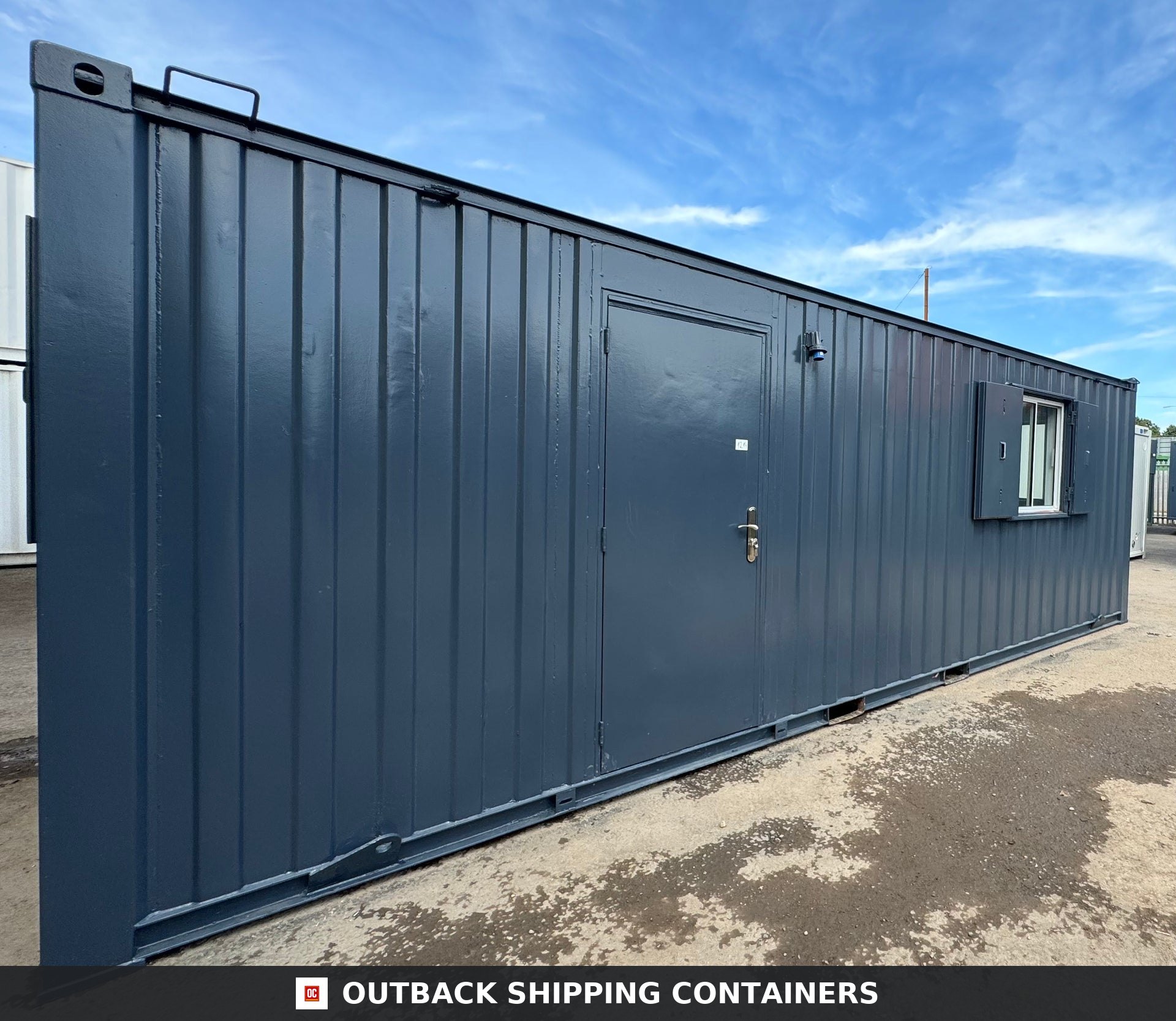 Side profile of a dark gray 24x9 ft anti-vandal office container with a steel door and one window under a clear sky