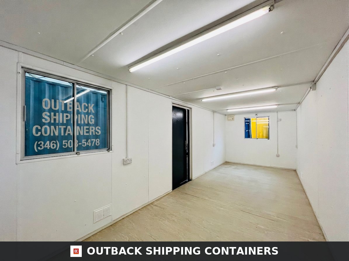 Interior of a refurbished 24x9 ft container office with white walls, fluorescent lighting, and two windows