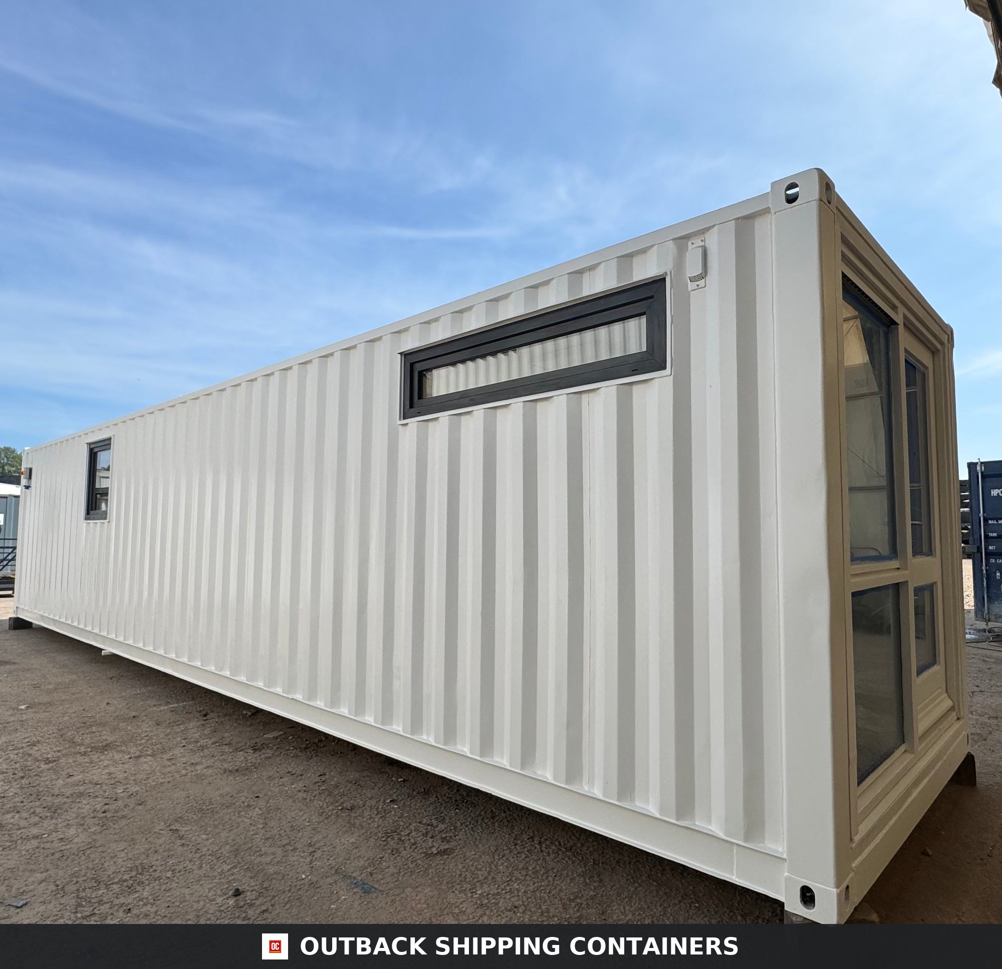 40ft white converted shipping container office with horizontal windows and glass door viewed from an exterior angle