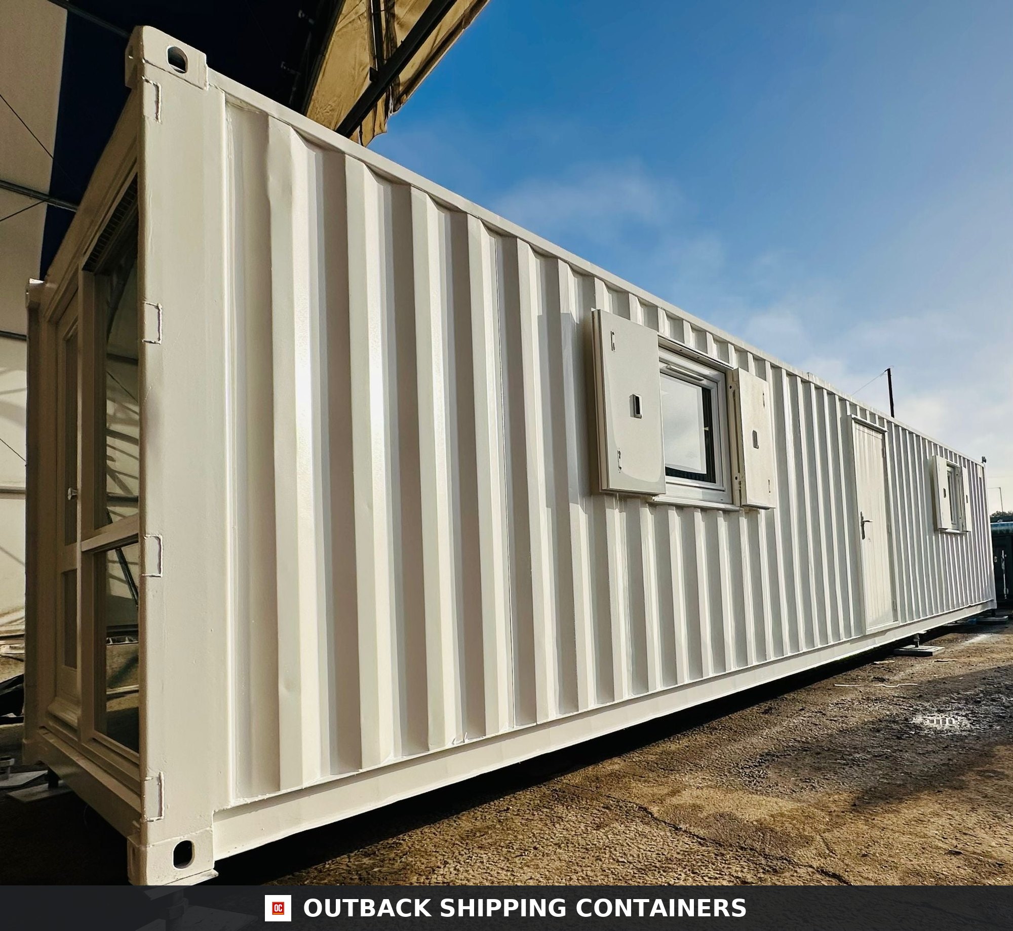 40ft white converted shipping container office with steel security shutters over glass windows and side door