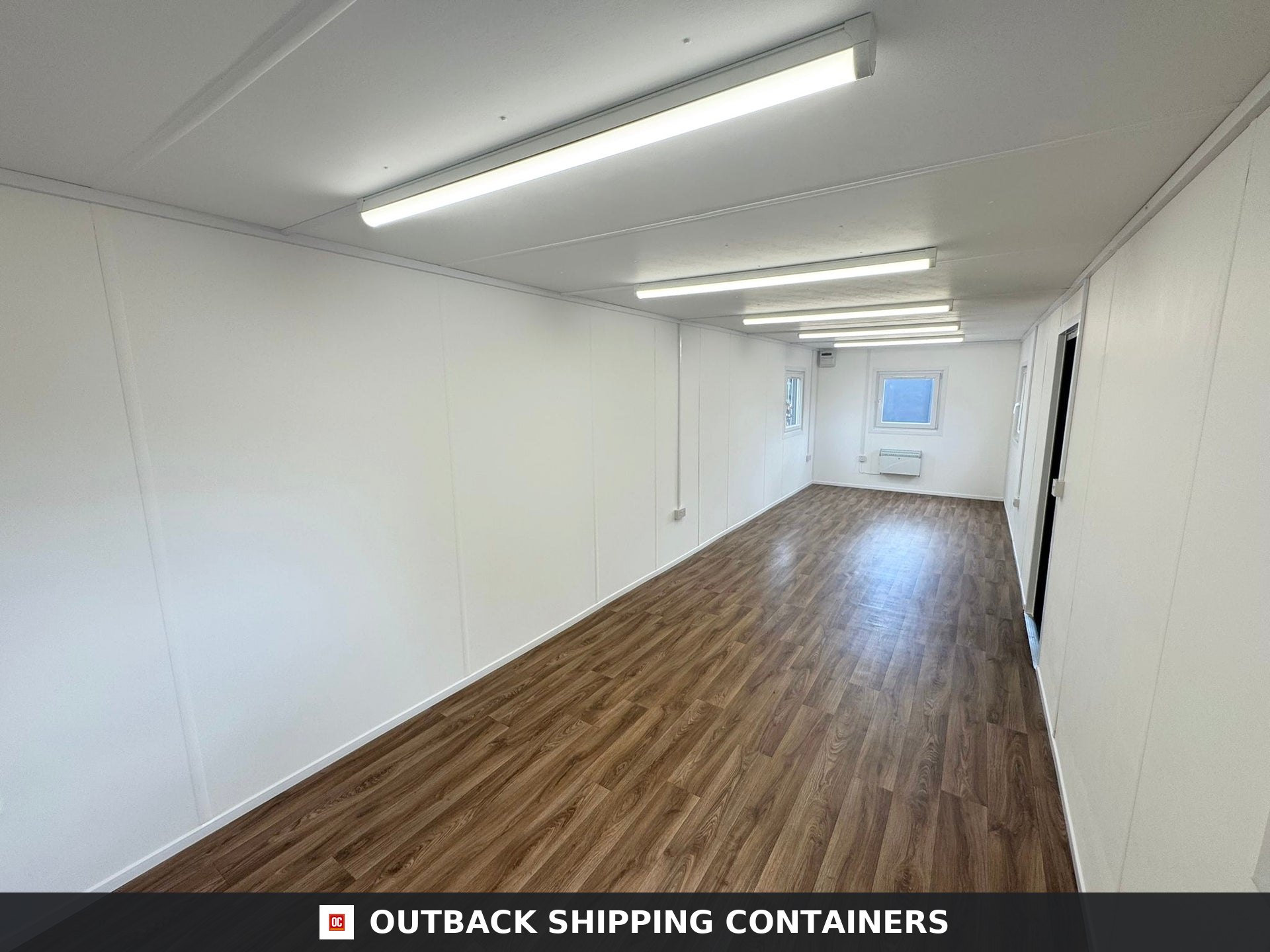32ft Cabin for Sale — Interior Detail | Outback Shipping Containers Refurbished 32ft open plan office interior with wood-effect flooring, white walls, and bright overhead LED lighting
