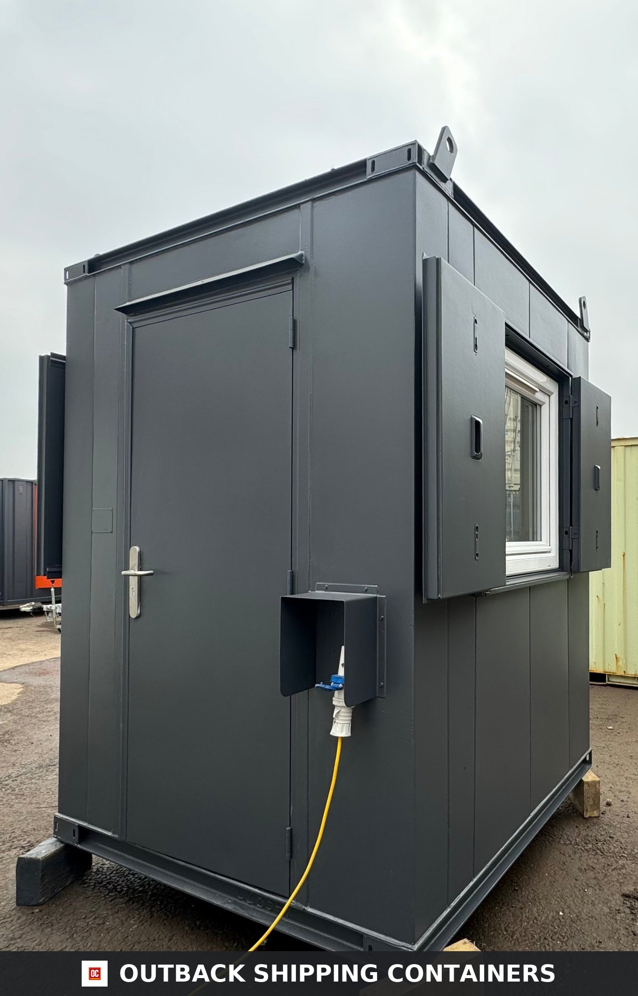 6x6 ft 6x6FT for Sale — Rear Exterior View | Outback Shipping Containers Dark gray 6x6 gate house security hut with steel anti-vandal door and window shutters