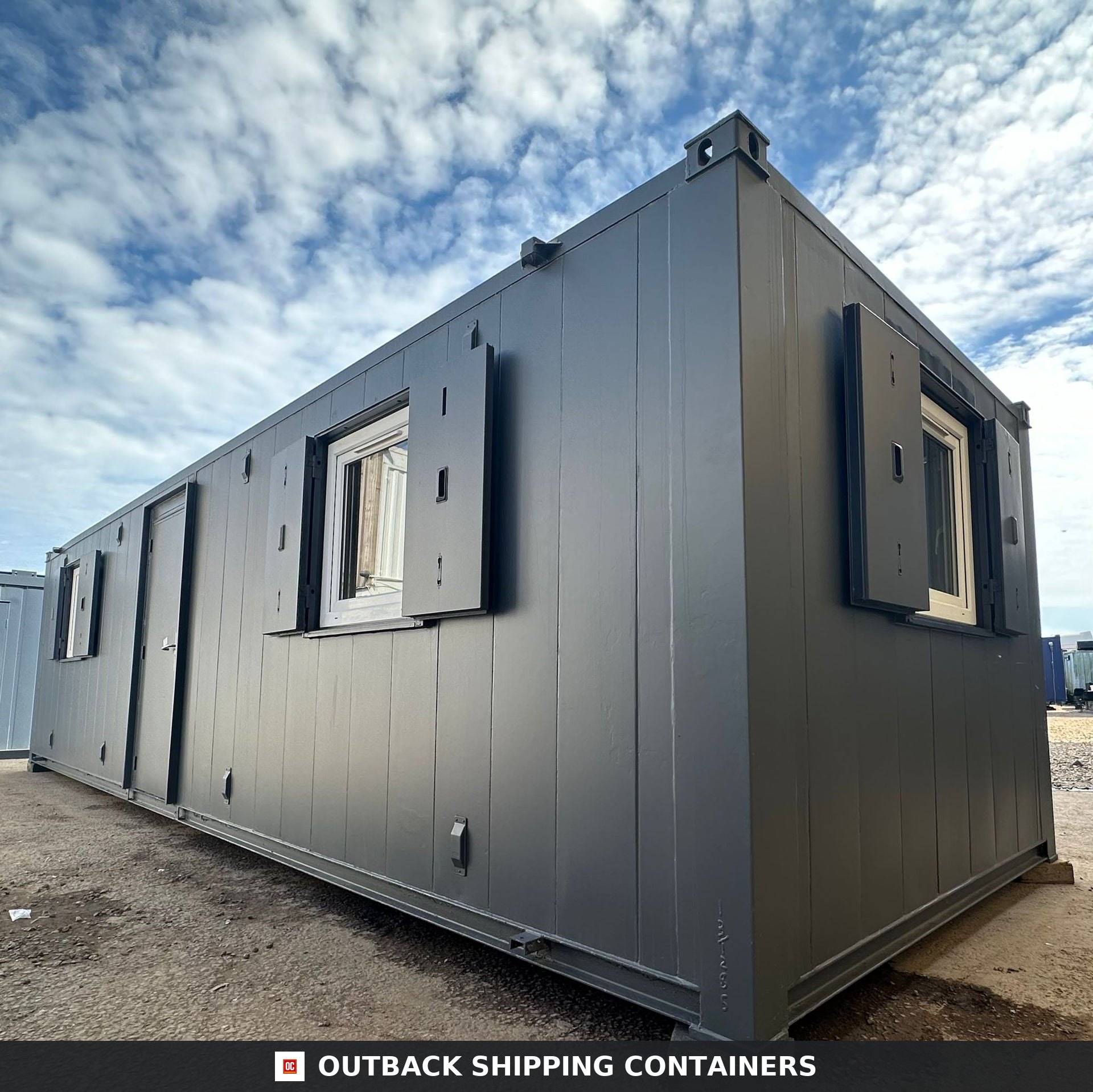 32x10ft Cabin for Sale — Interior View | Outback Shipping Containers 2 Refurbished 32x10 shipping container office with grey anti-vandal steel shutters and exterior door under a blue sky