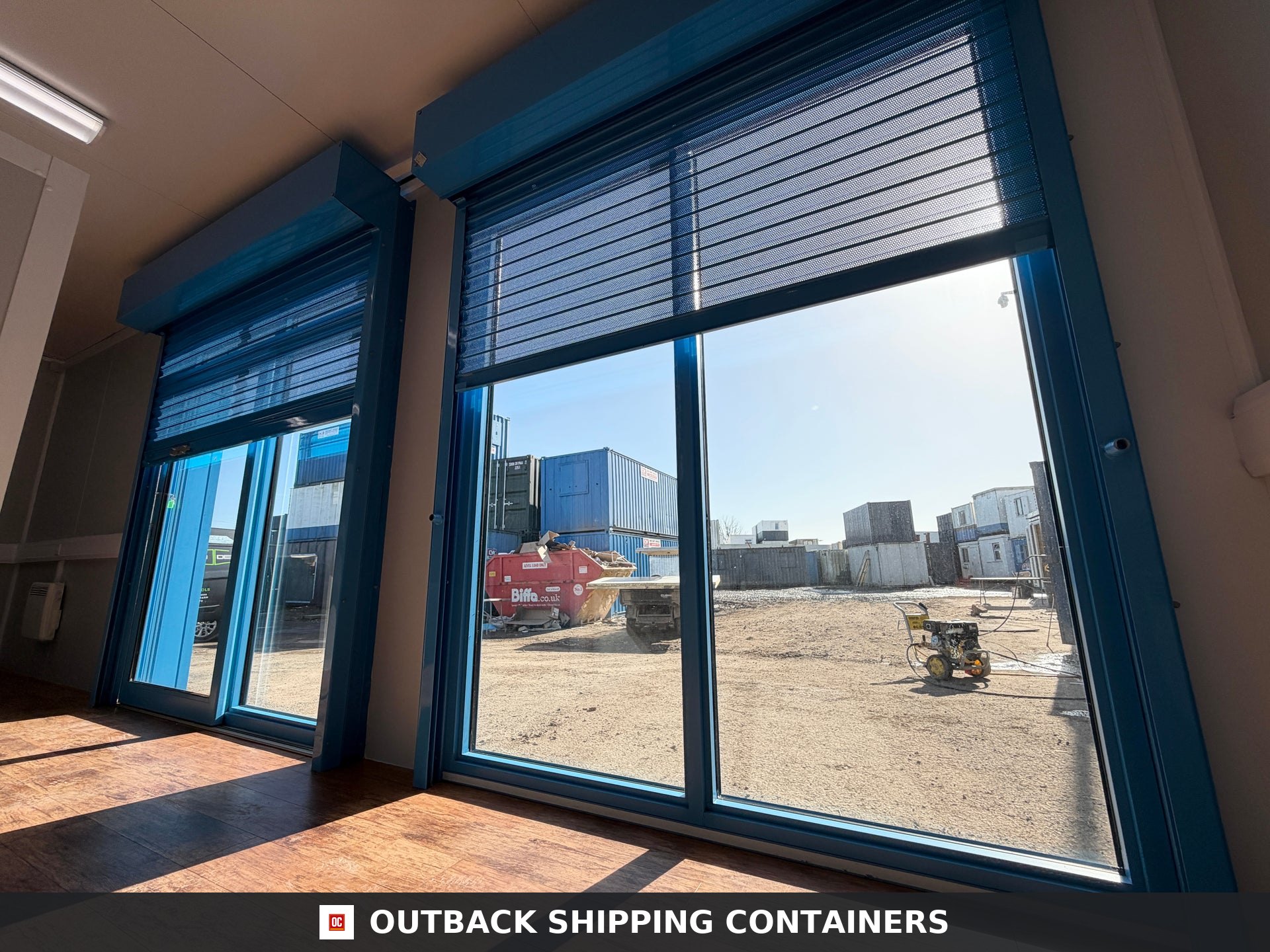 26x12ft for Sale — Interior View | Outback Shipping Containers Interior view of a portable marketing suite featuring large glass windows with blue security roller shutters