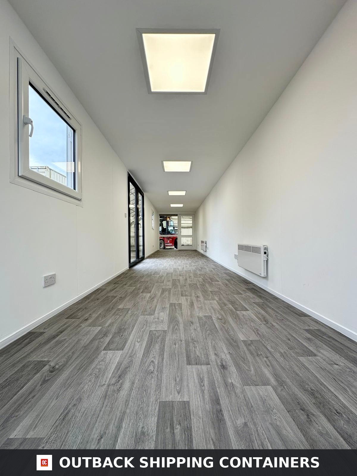 40ft shipping container office interior with wood-look flooring, white walls, LED ceiling lights, and wall heaters