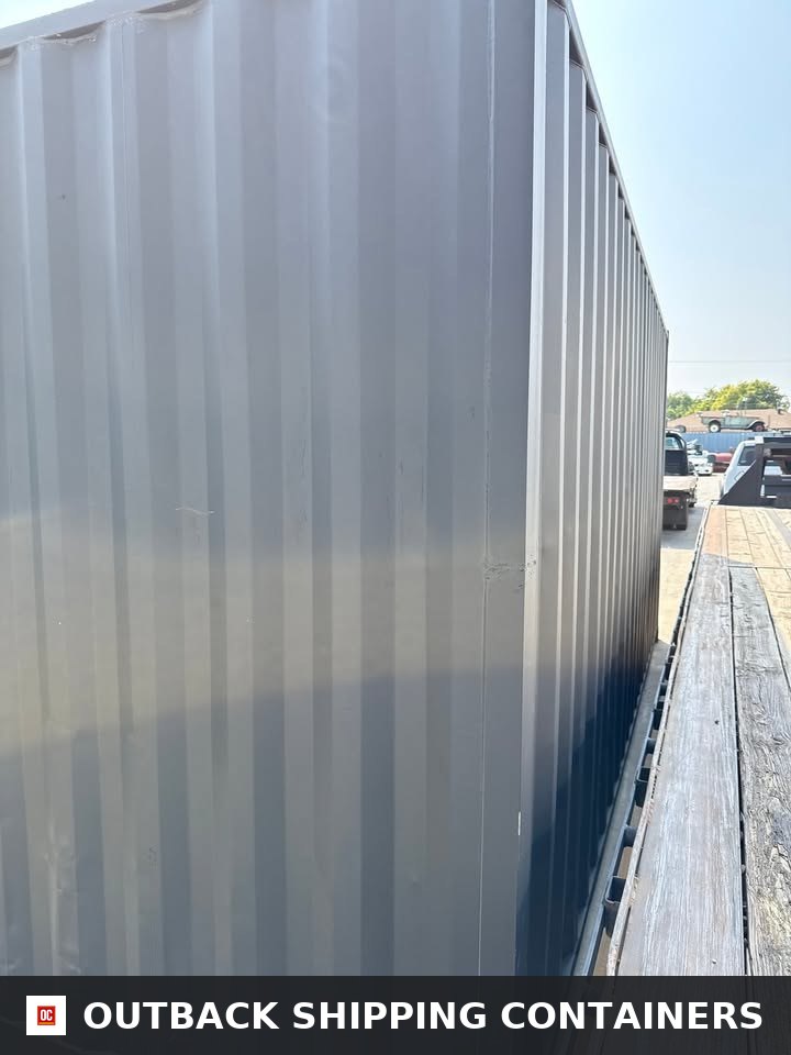 20ft Used Shipping Container for Sale — Three-Quarter Angle View | Outback Shipping Containe 15 Side profile of a matte black 20ft shipping container showing corrugated steel texture on a flatbed trailer