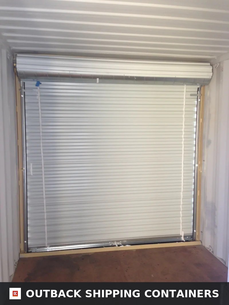 20ft Custom One Trip Shipping Container for Sale — Interior View | Outback Shipping Containers Interior view of a shipping container with a white roll-up shutter door installed on a side wall
