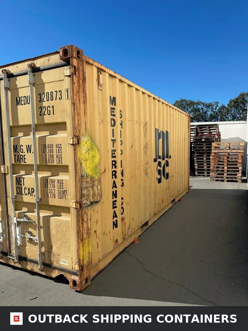Used 20ft conex shipping container in yellow with rust on door frame and corrugated side panel outdoors
